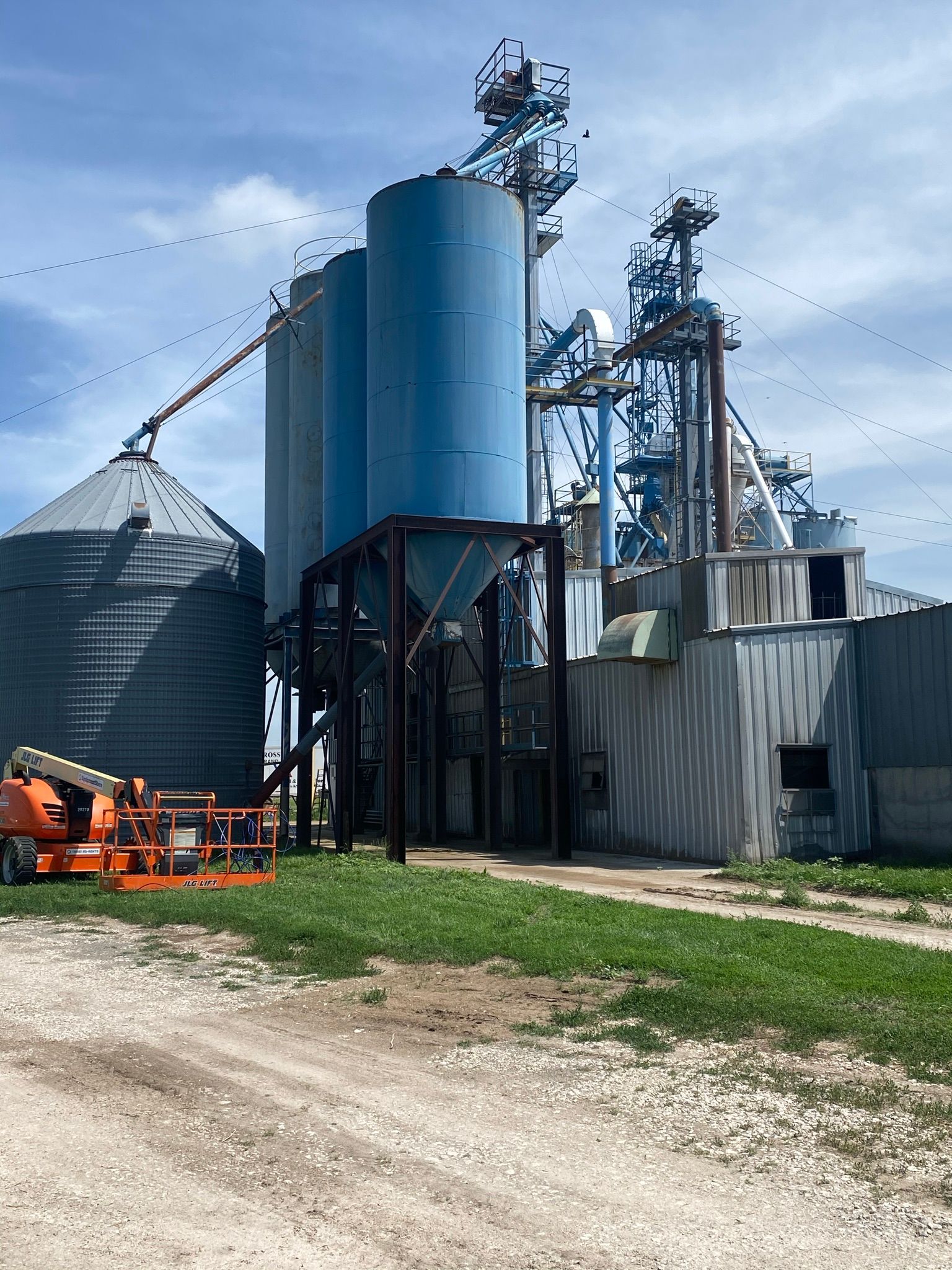 Grain silos and processing equipment under a partly cloudy sky.
