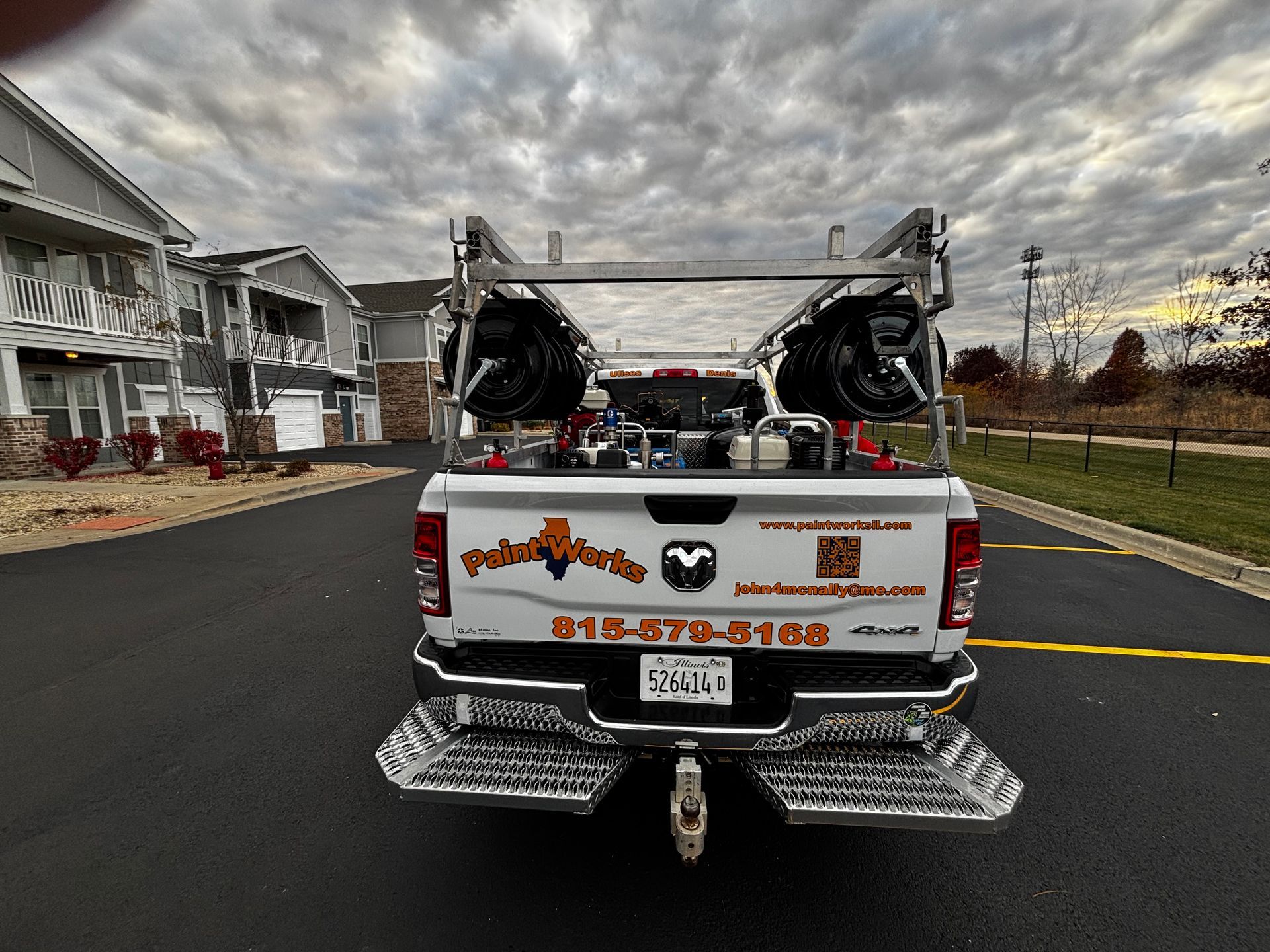 White Ram truck with equipment rack and trailer hitch, parked on asphalt. 