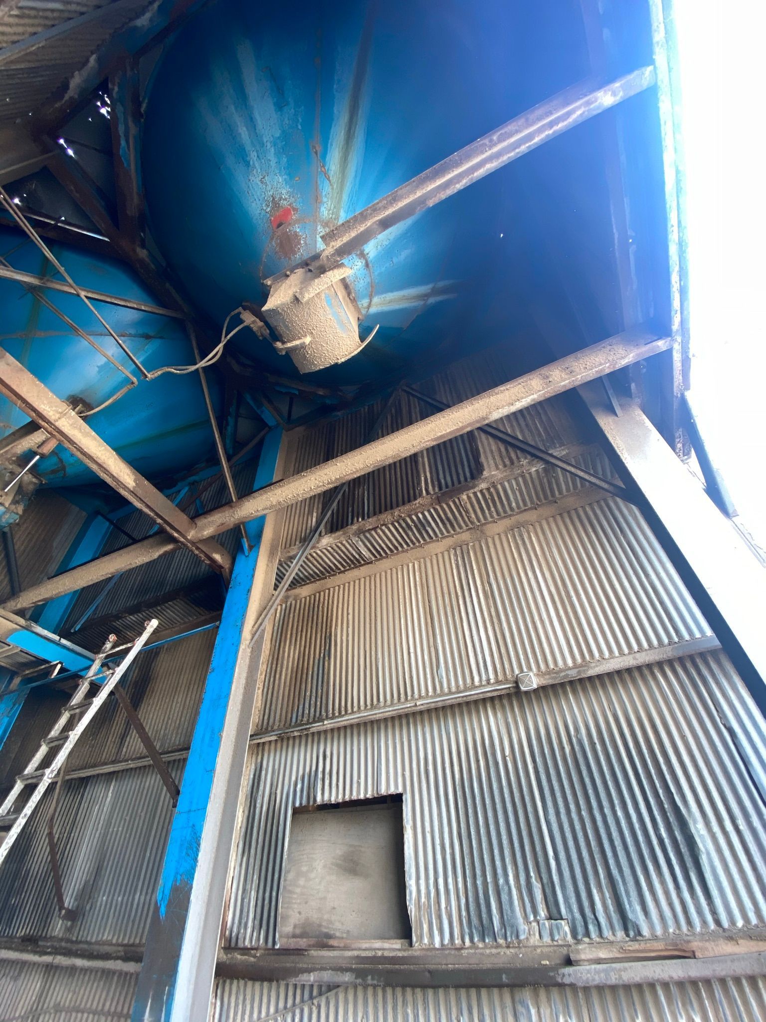 Interior view of a blue, corrugated metal silo with wooden beams and ladder.