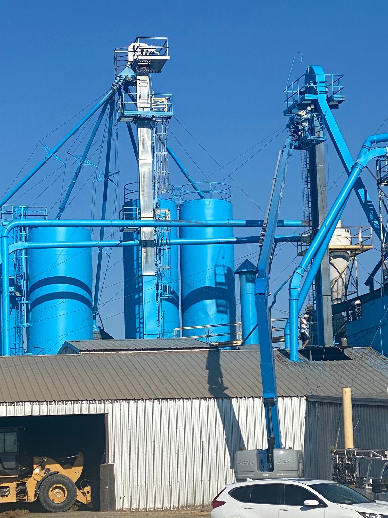 Blue industrial silos and machinery, exterior shot.