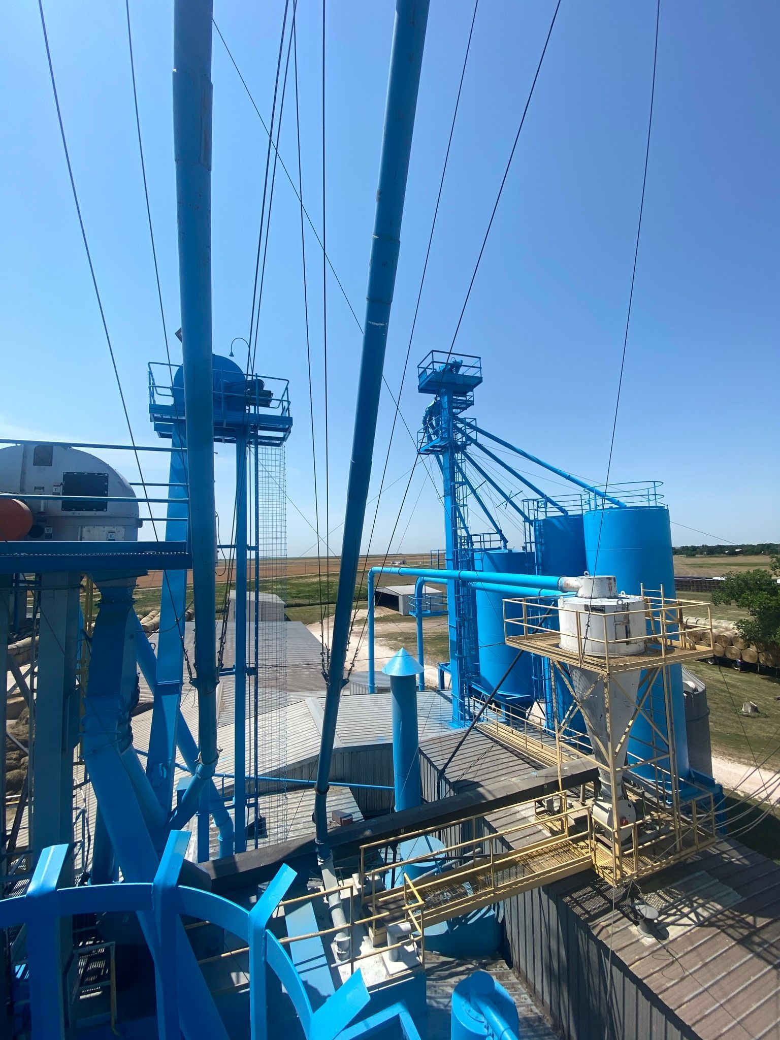 Blue industrial grain facility against a clear, sunny sky.