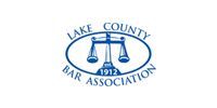 The lake county bar association logo is a blue and white logo with a scale of justice.