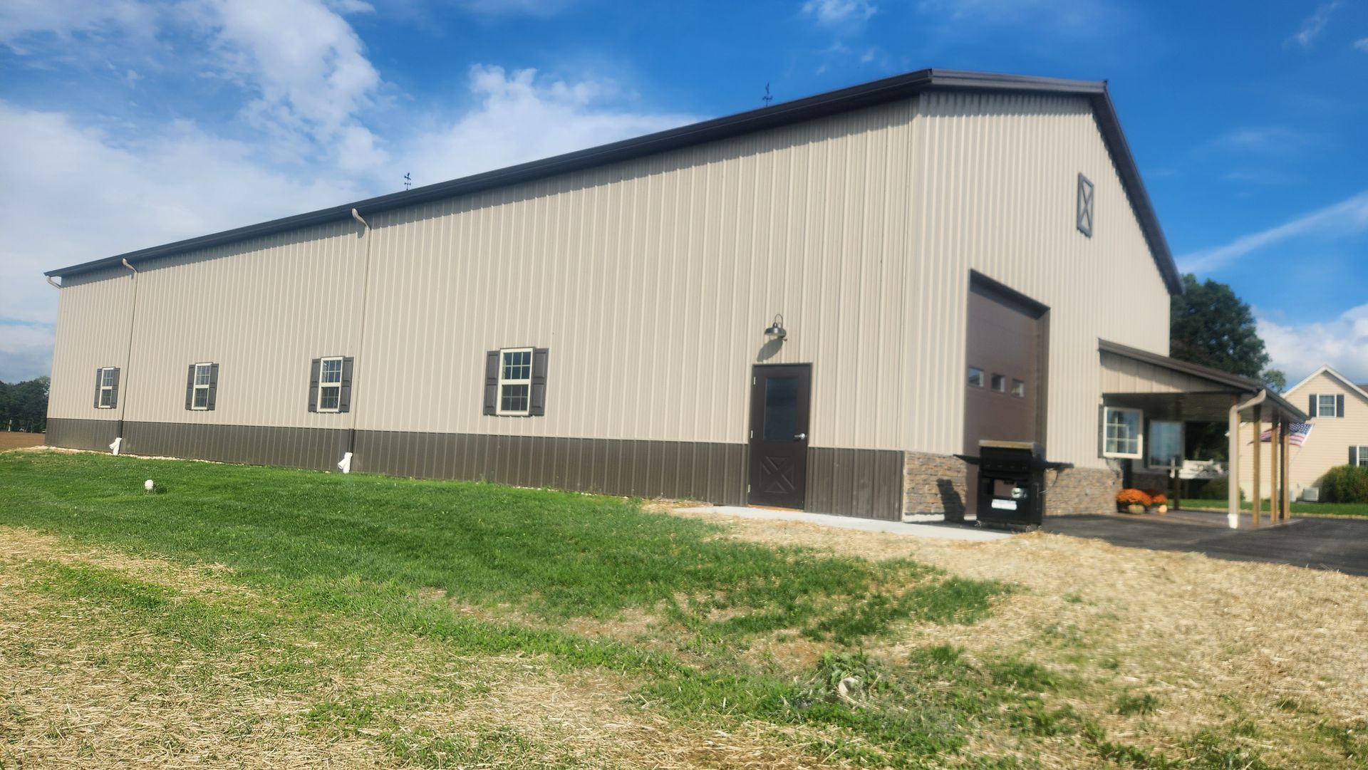 A large metal building is sitting in the middle of a grassy field.