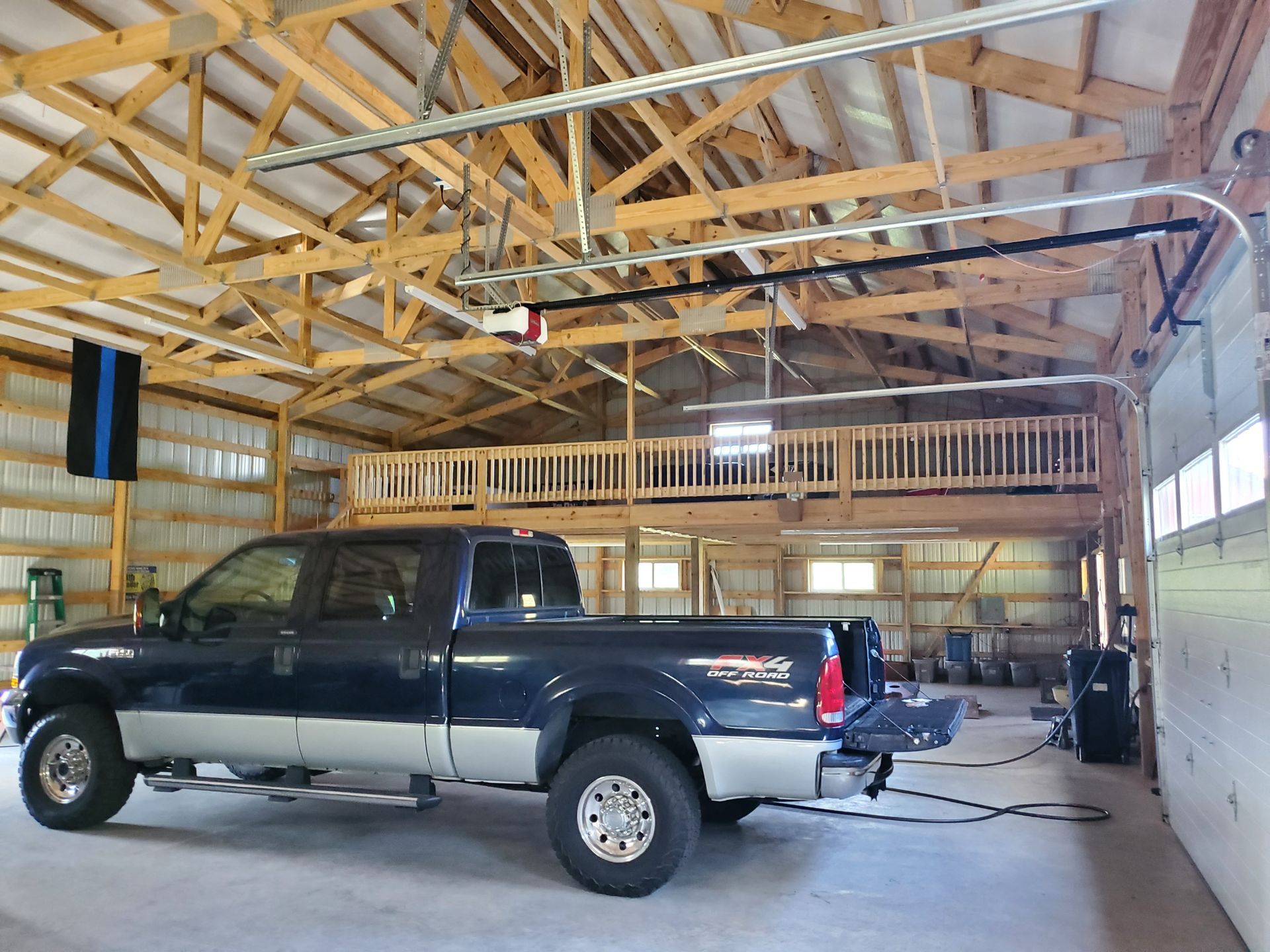 A truck is parked in a garage with a black and white flag hanging from the ceiling.