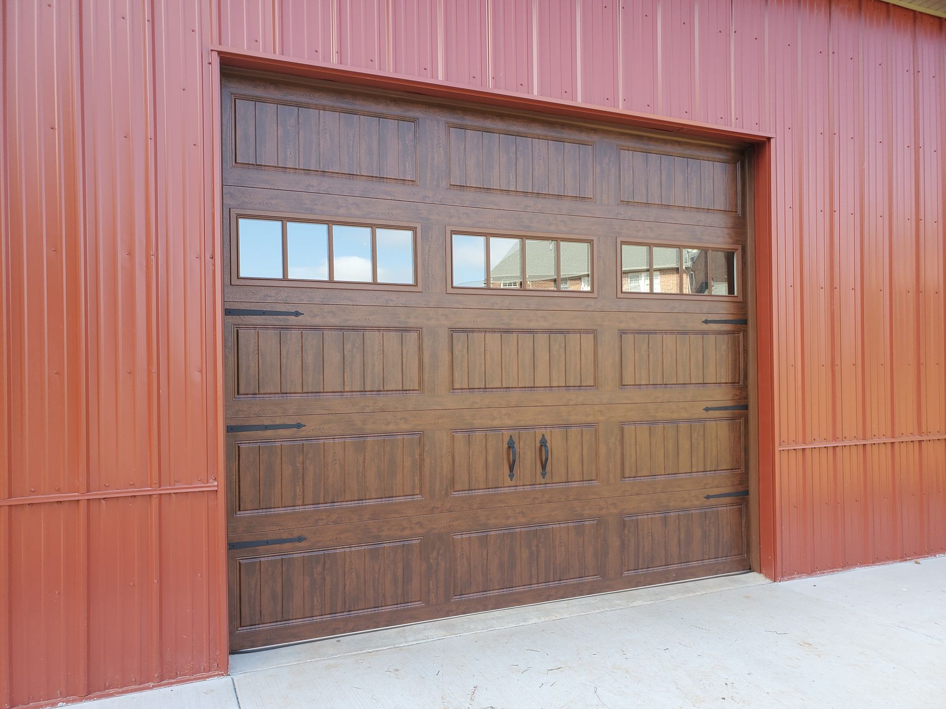 A brown garage door is sitting on the side of a red building.