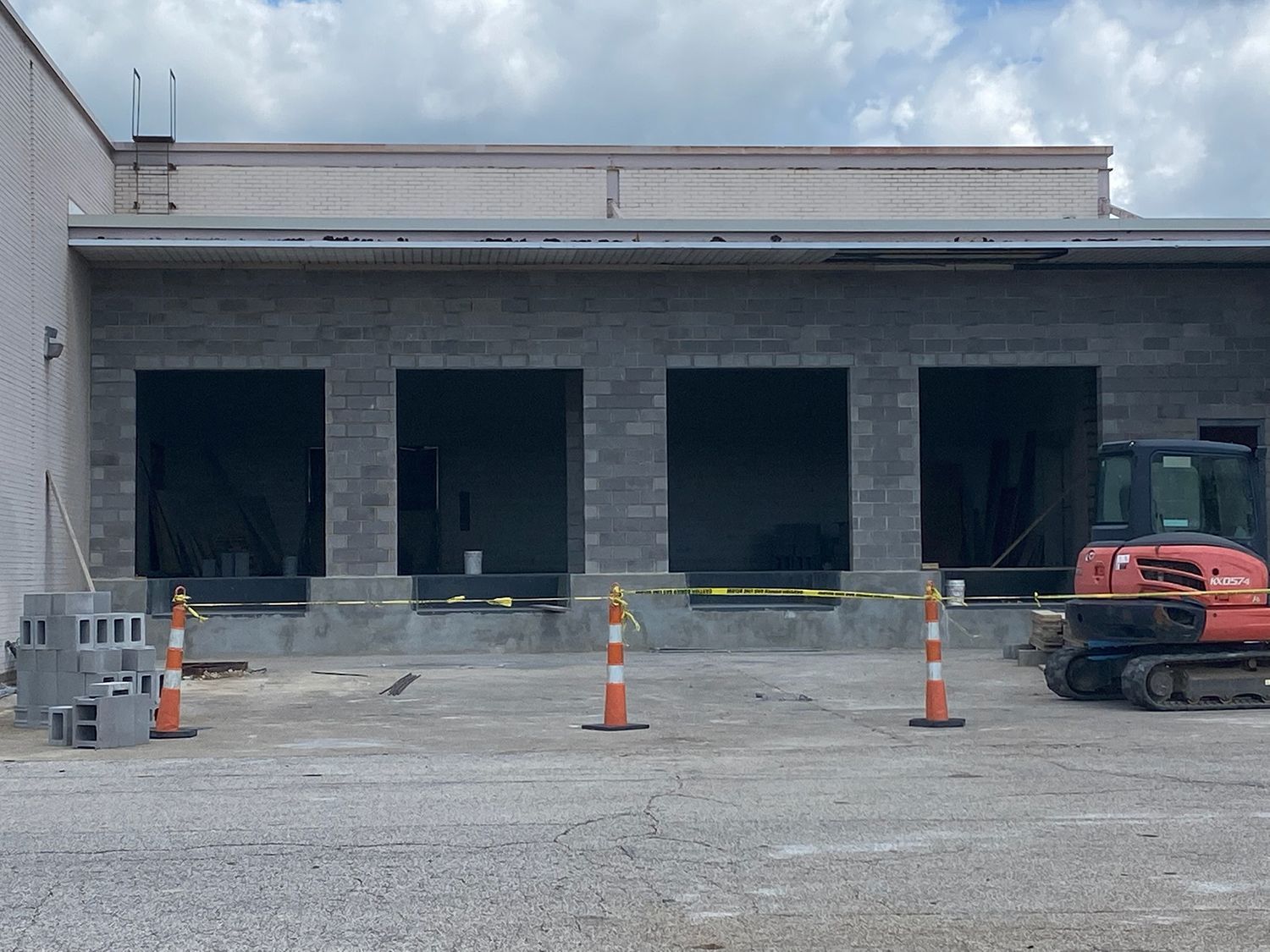 A red excavator is parked in front of a building under construction.