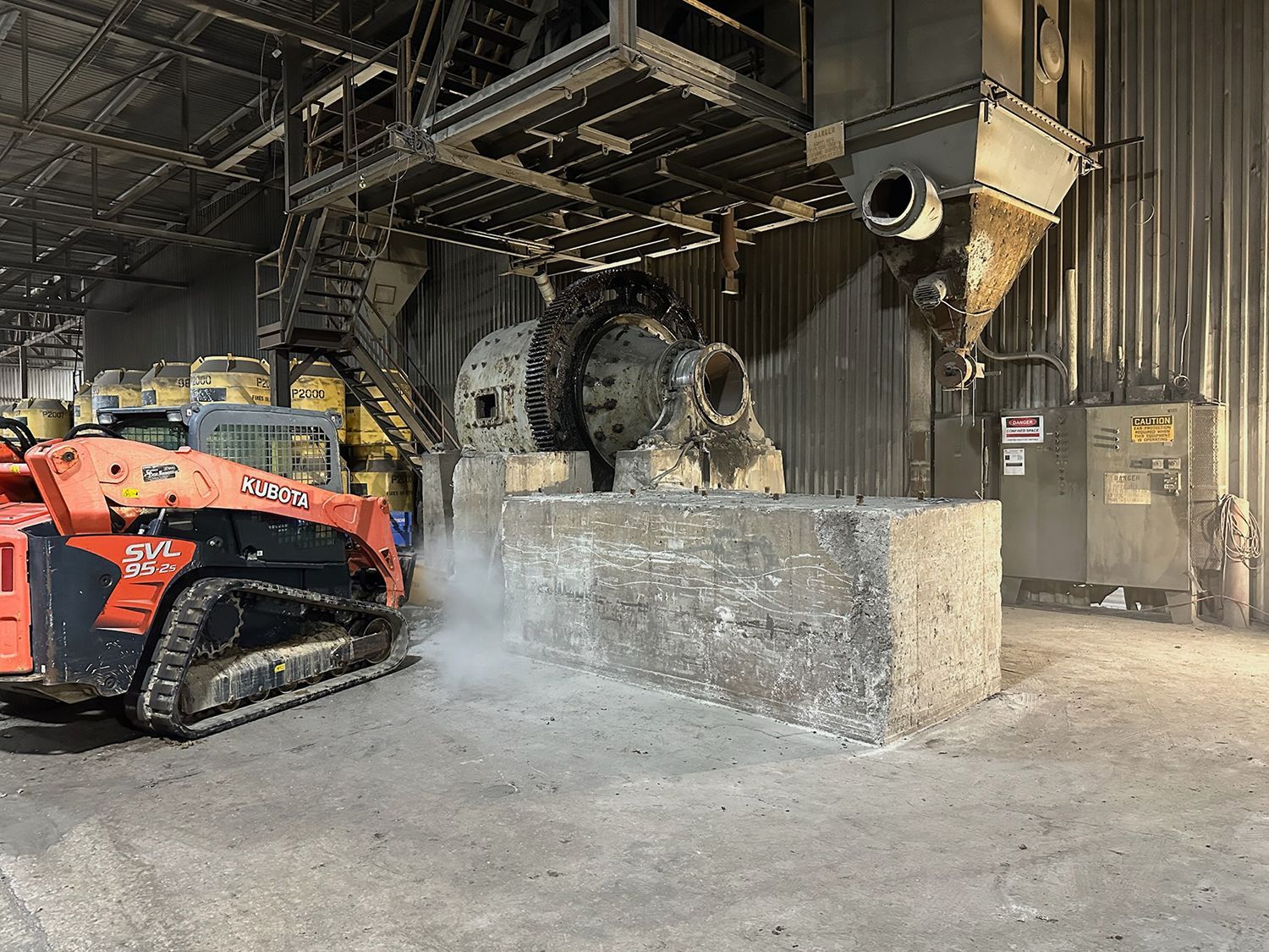 A bulldozer is sitting in a warehouse next to a machine.