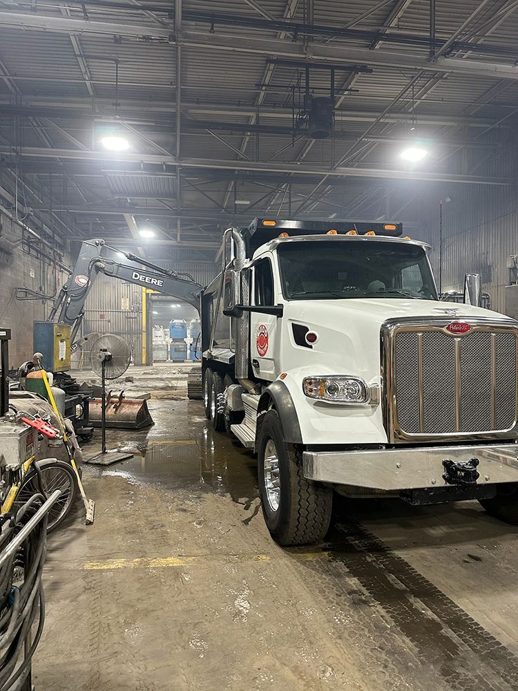 A white dump truck is parked in a warehouse.