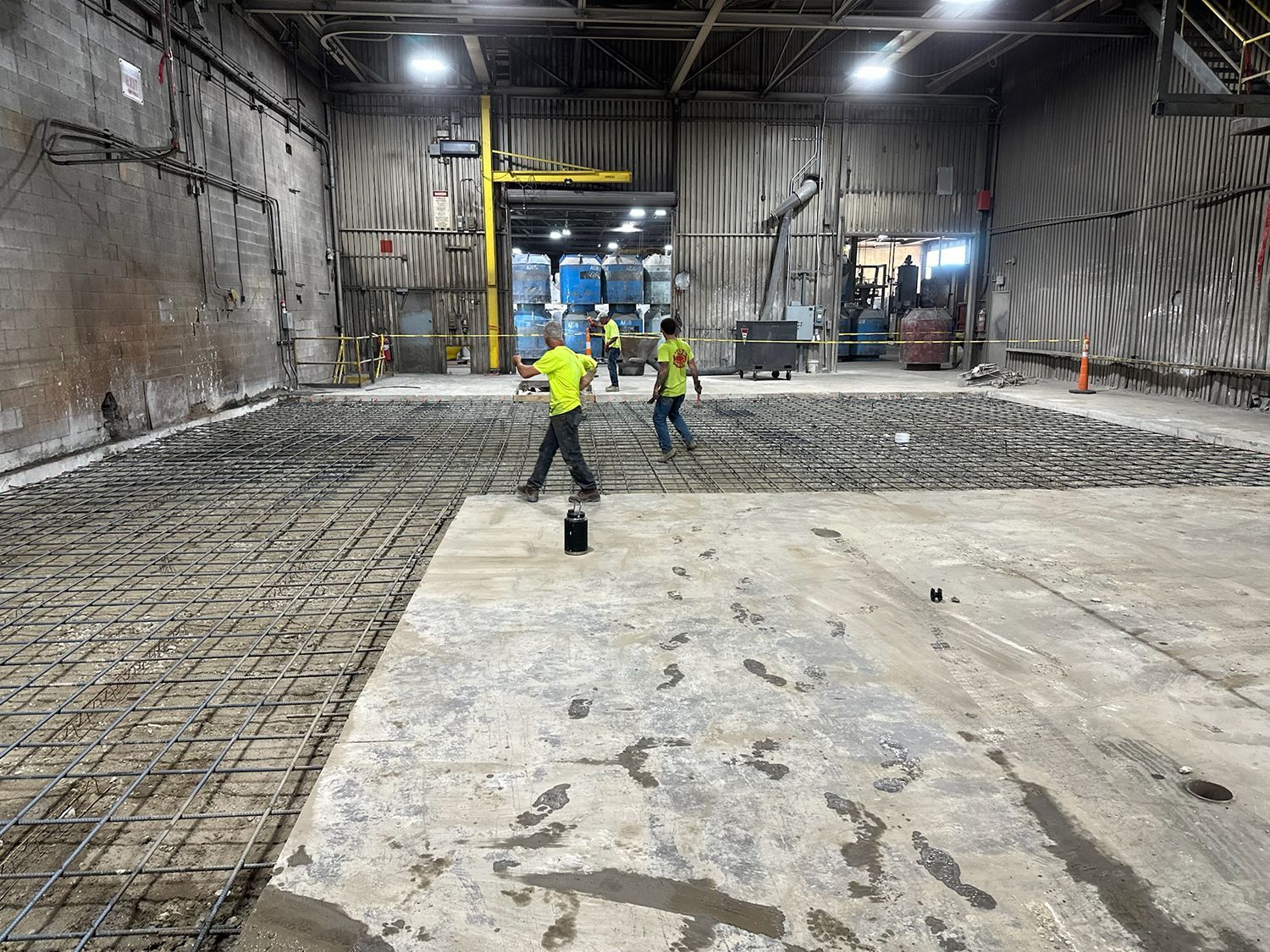 A group of construction workers are working in a large warehouse.