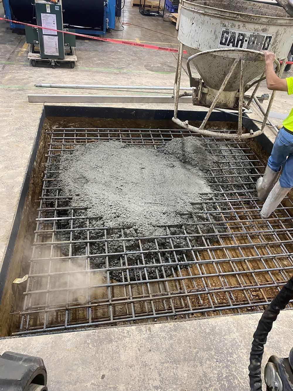 A man is pouring concrete into a hole in the ground.