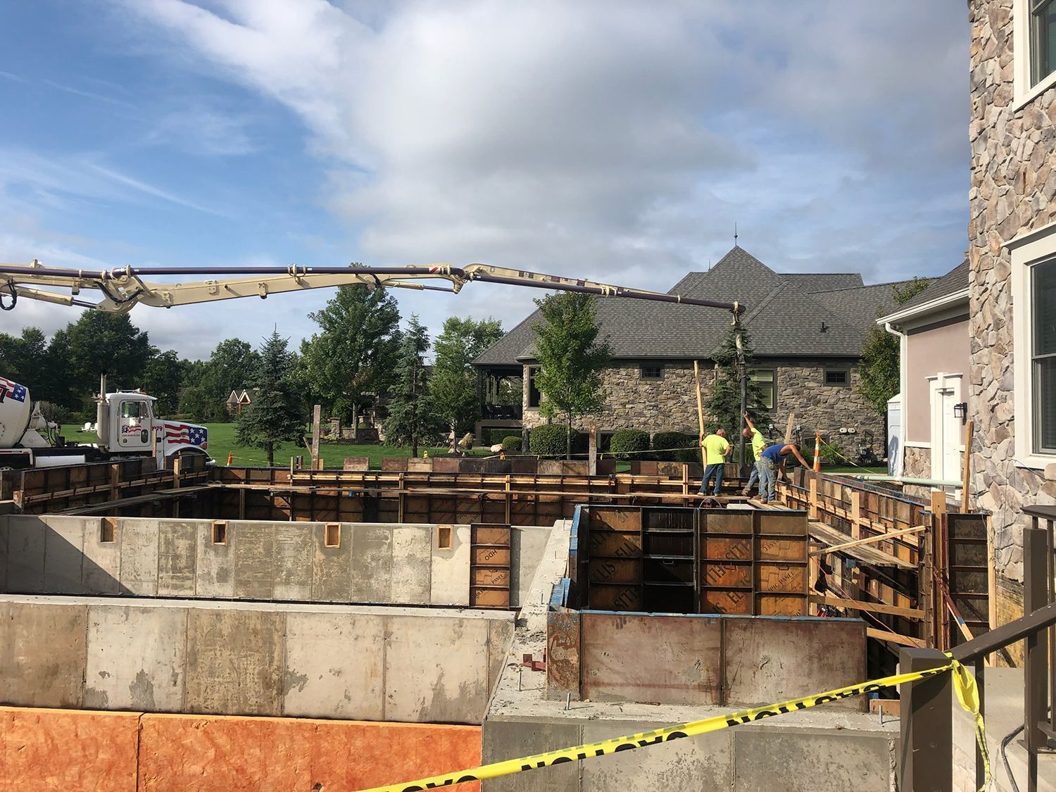 A concrete pump is being used to pour concrete into a foundation of a house.