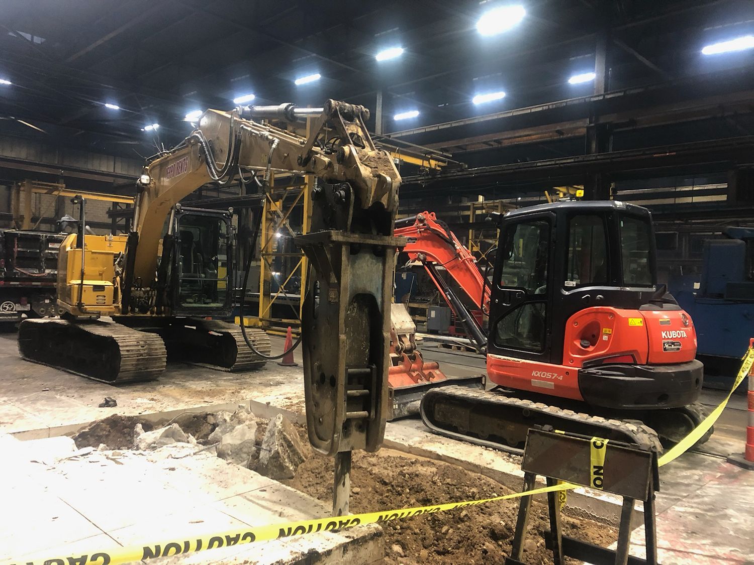 A couple of construction vehicles are parked in a garage.