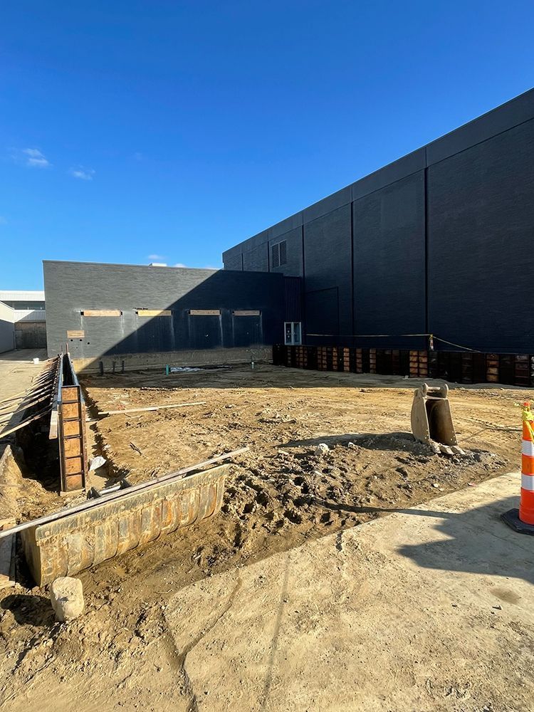 A large building is being built in the middle of a dirt field.