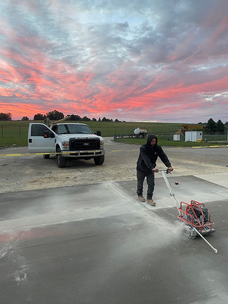 A man is using a machine to cut concrete in a parking lot.