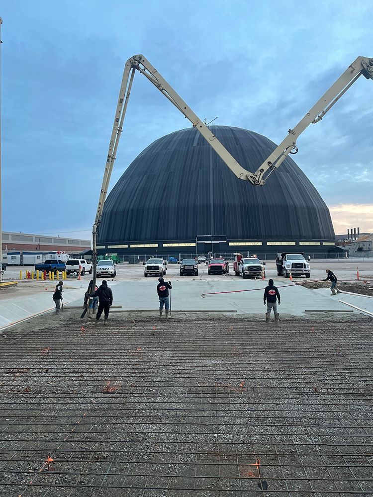 A group of people are working on a construction site in front of a large dome.