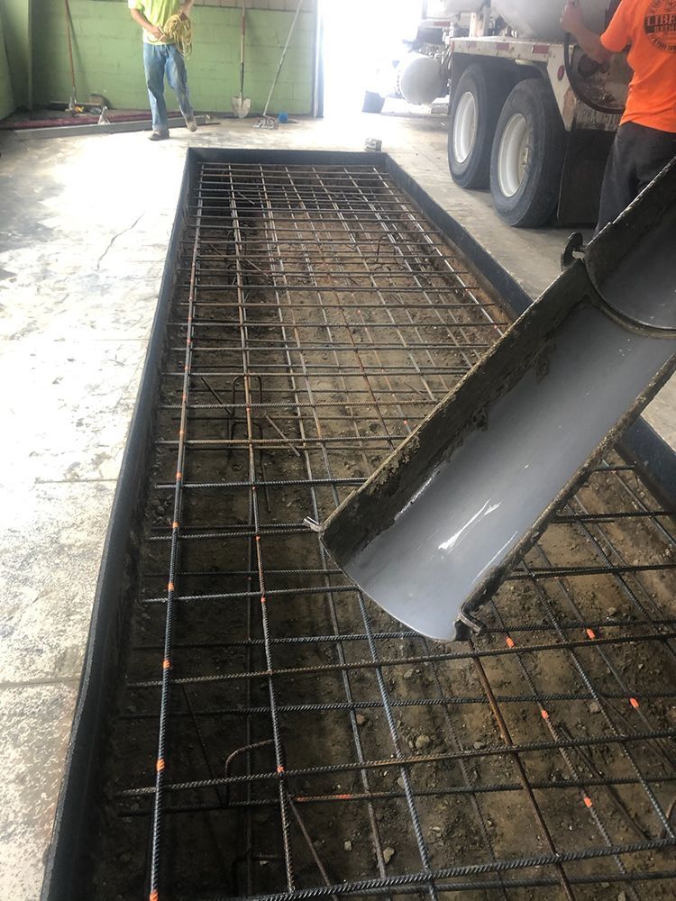 A man is pouring concrete into a hole in the ground.