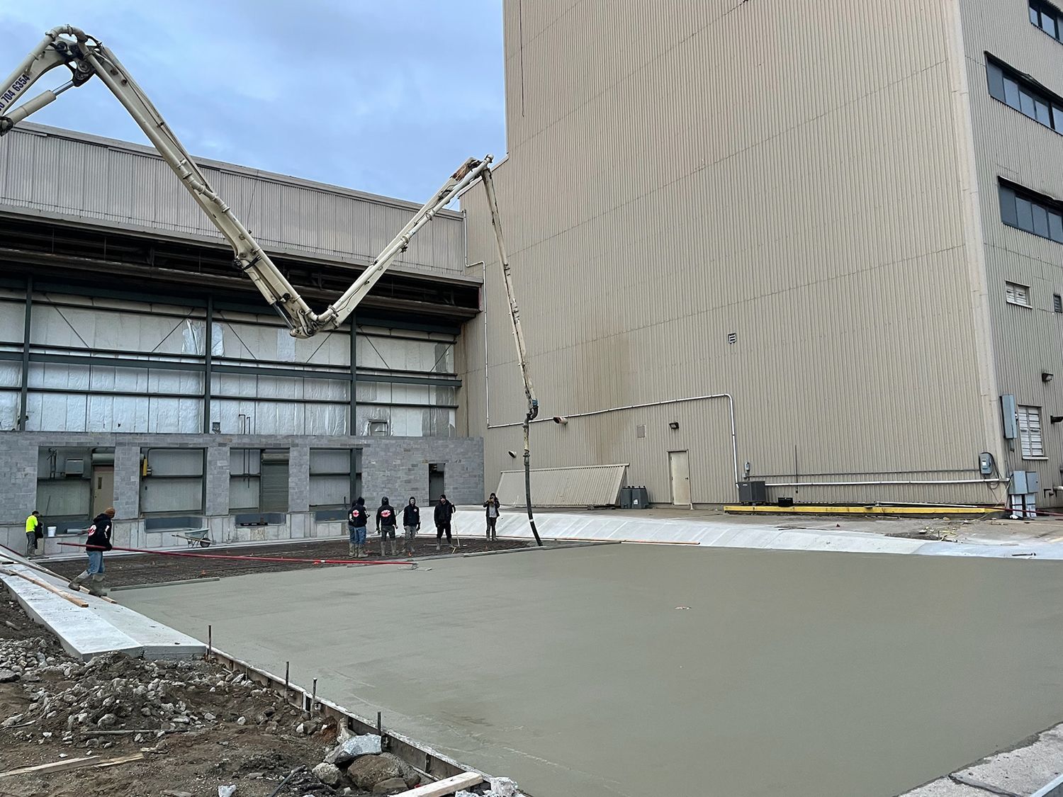 A concrete pump is being used to pour concrete in front of a large building.