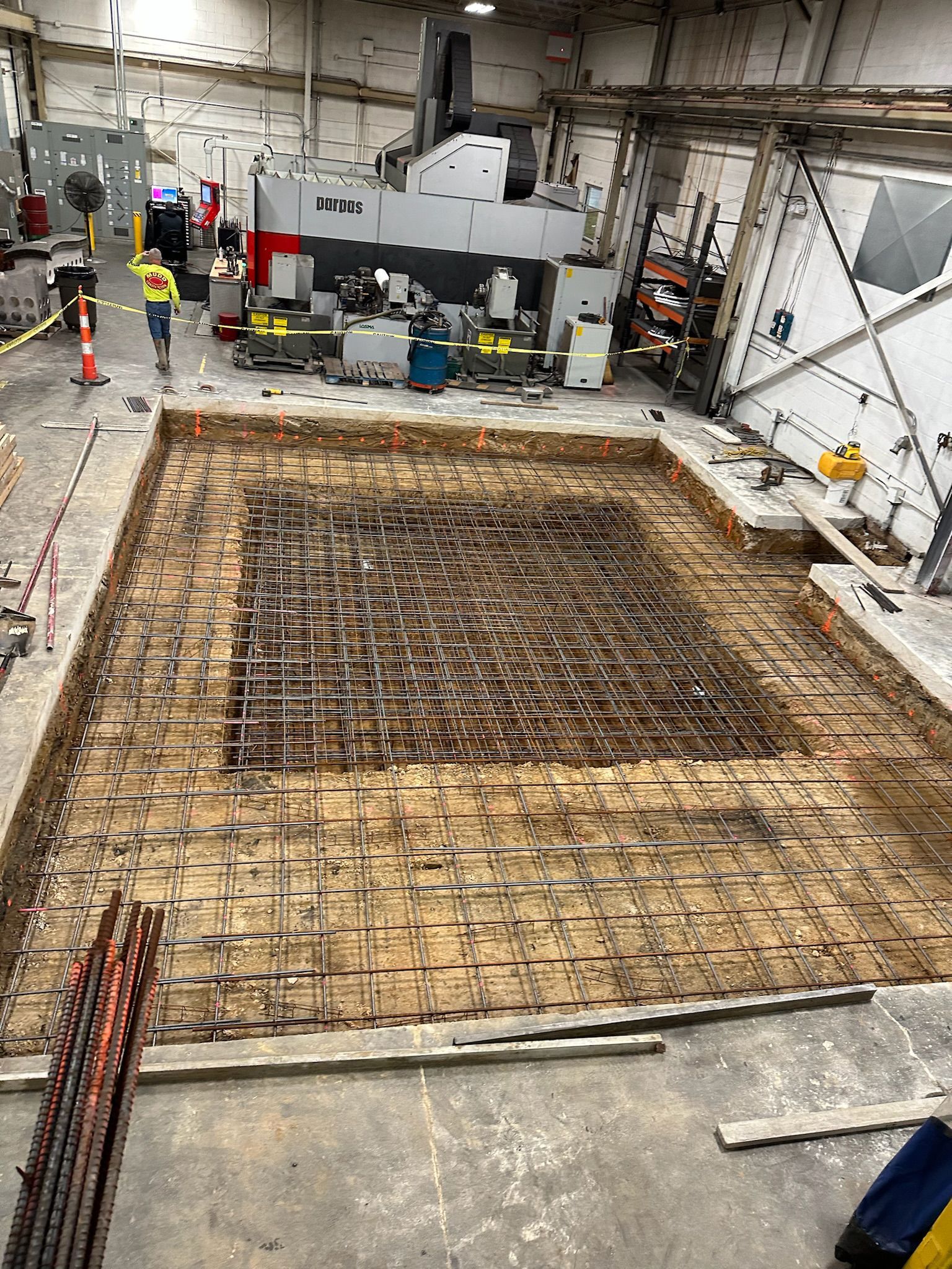 A large hole in the floor of a building with a machine in the background.