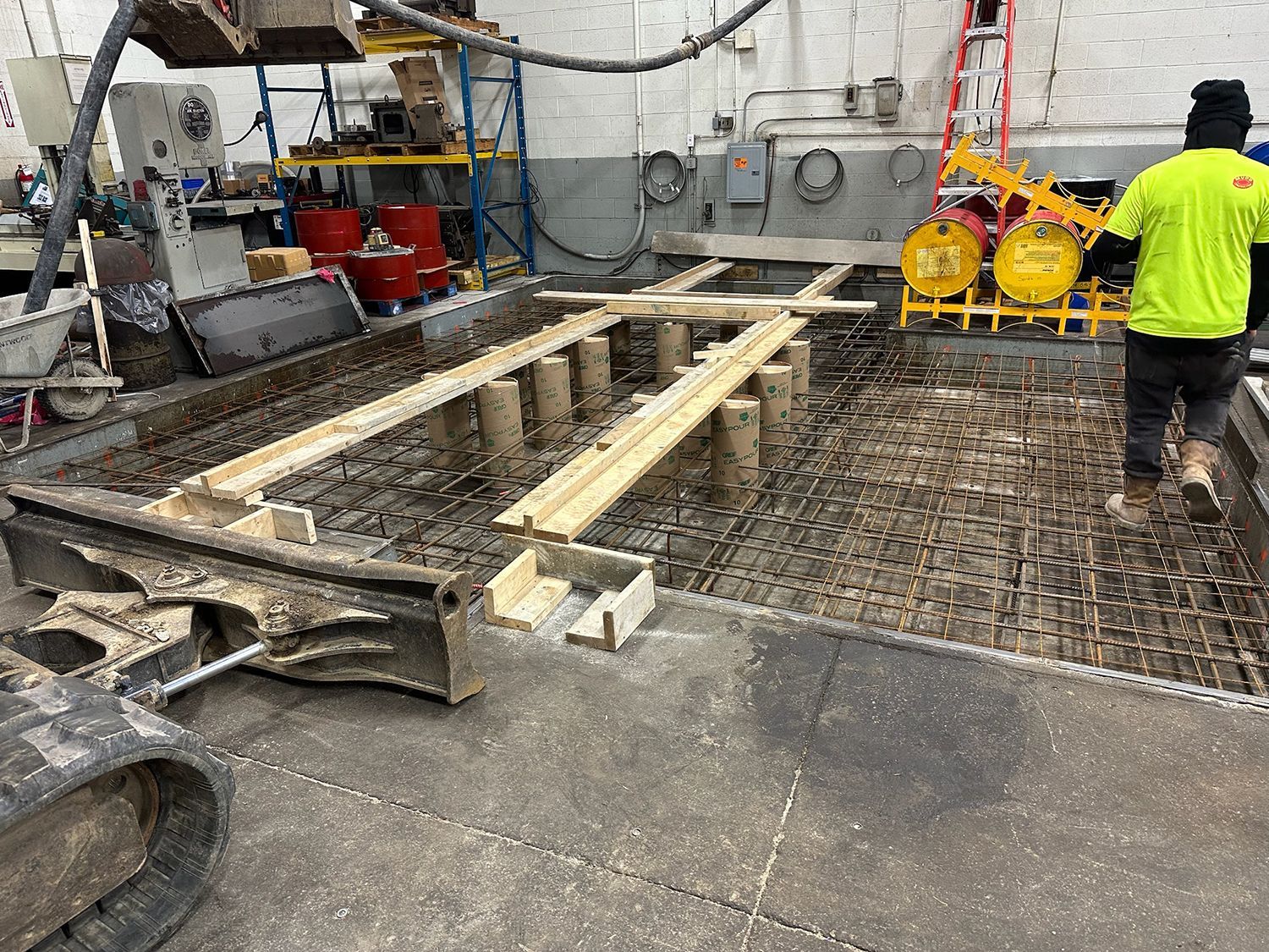 A man is working on a concrete floor in a factory.