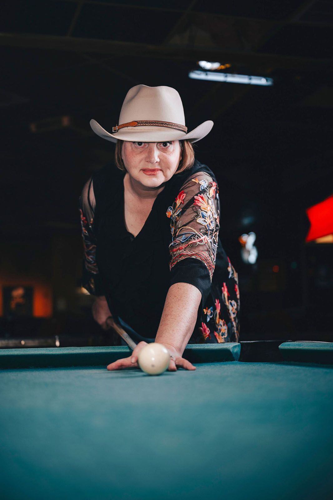 Woman in cowboy hat playing billiards