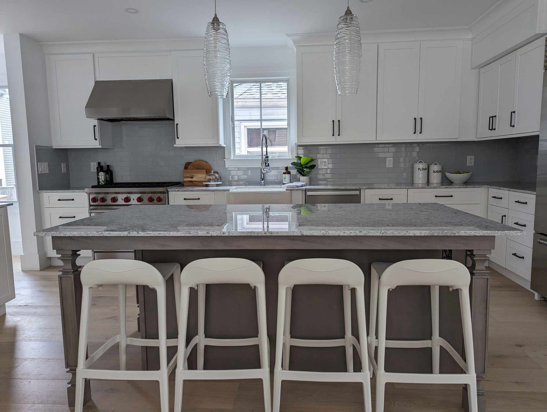 A kitchen with a large island and white stools.