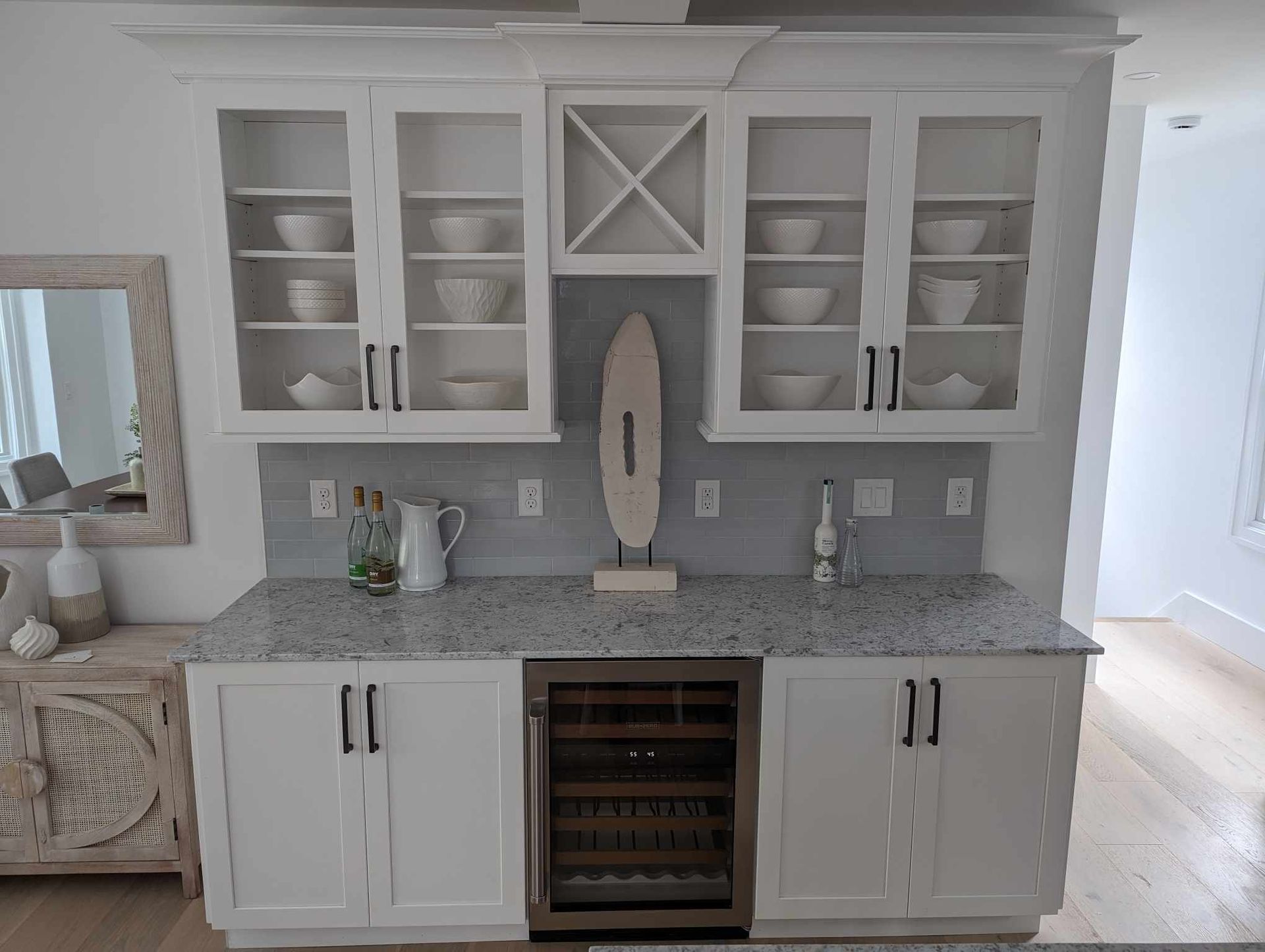 A kitchen with white cabinets, granite counter tops, and a wine cooler.