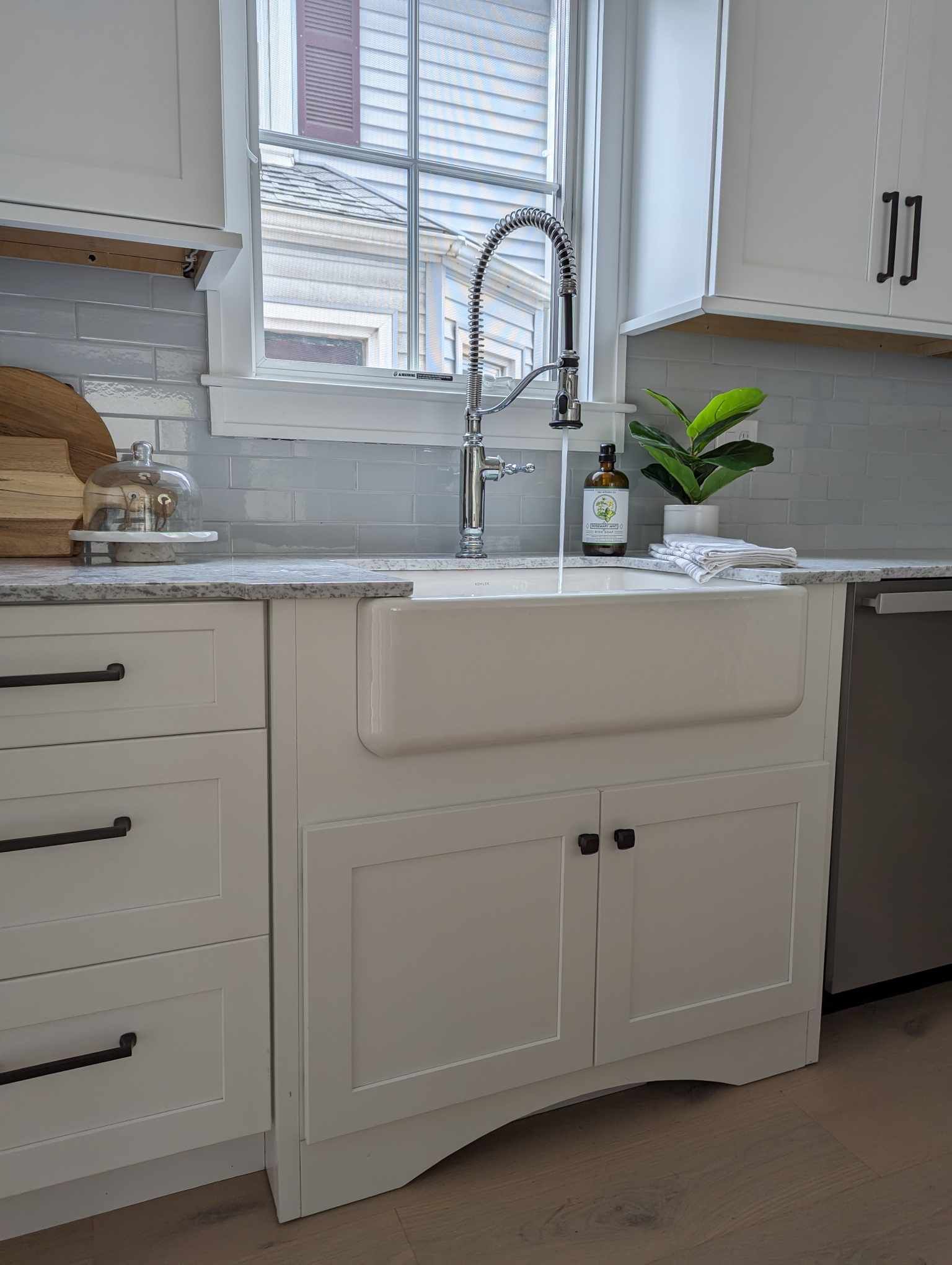 A kitchen with a white sink and a window.