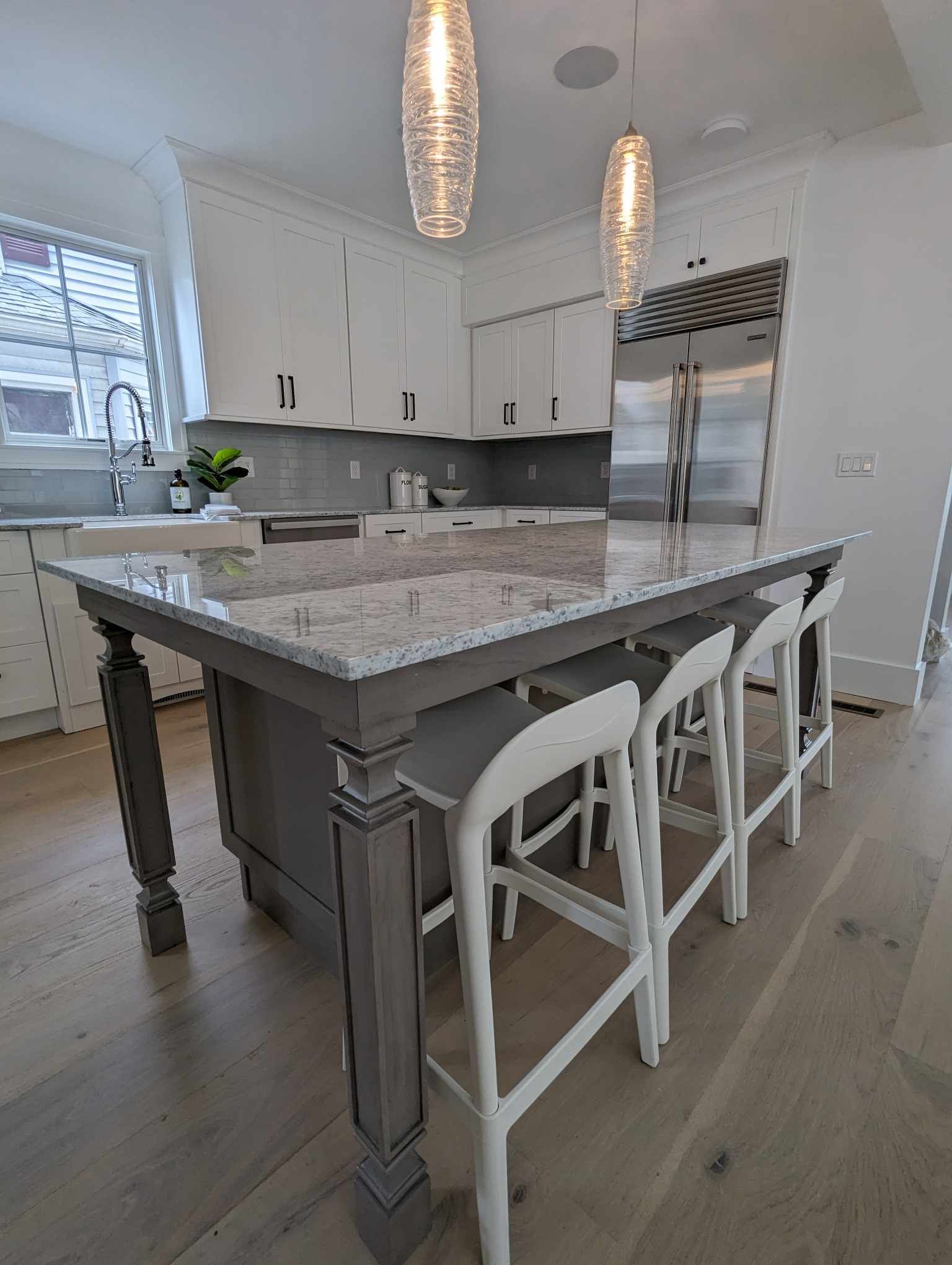 A kitchen with a large island and white stools.