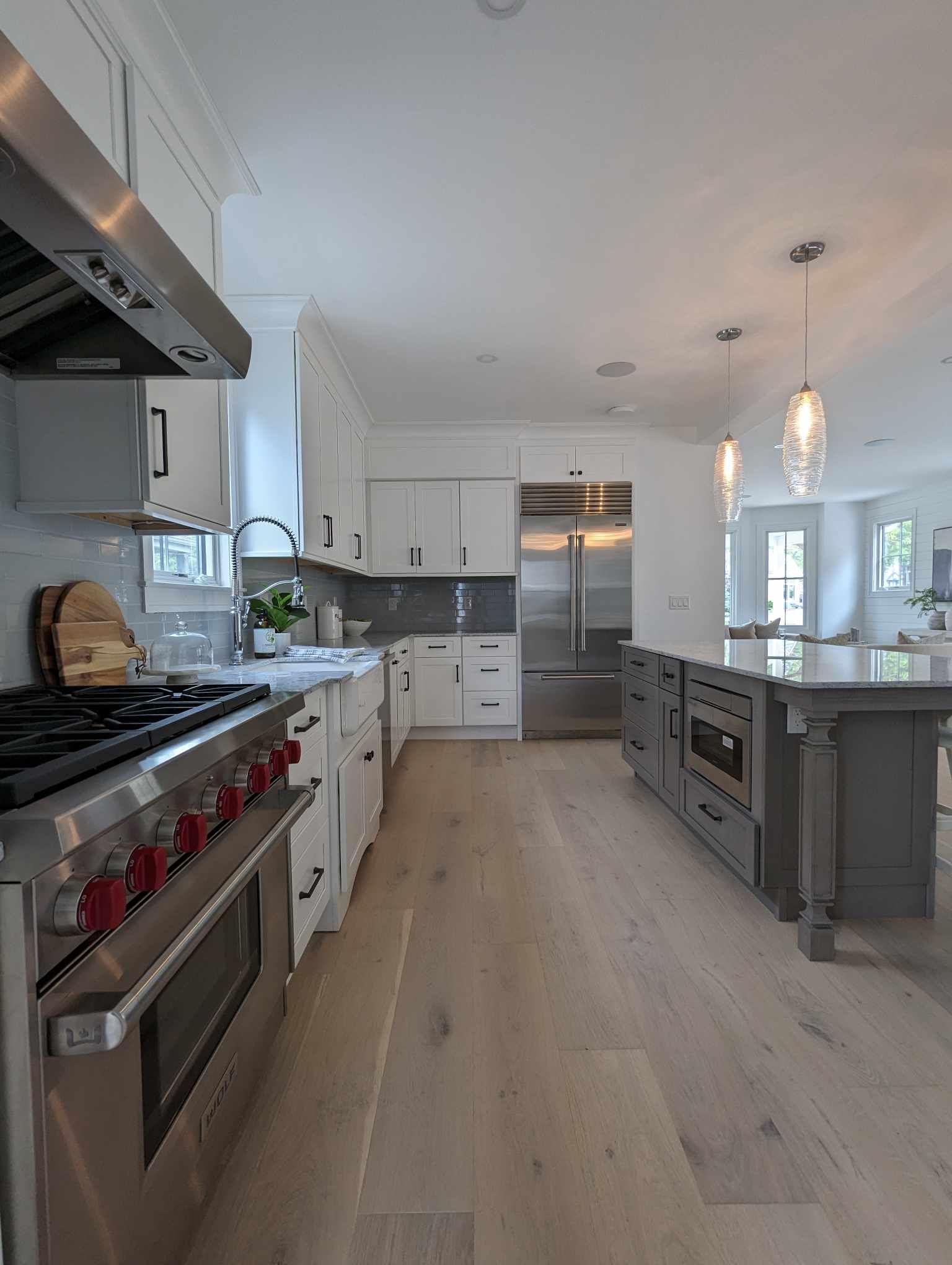A kitchen with stainless steel appliances, white cabinets, hardwood floors and a large island.