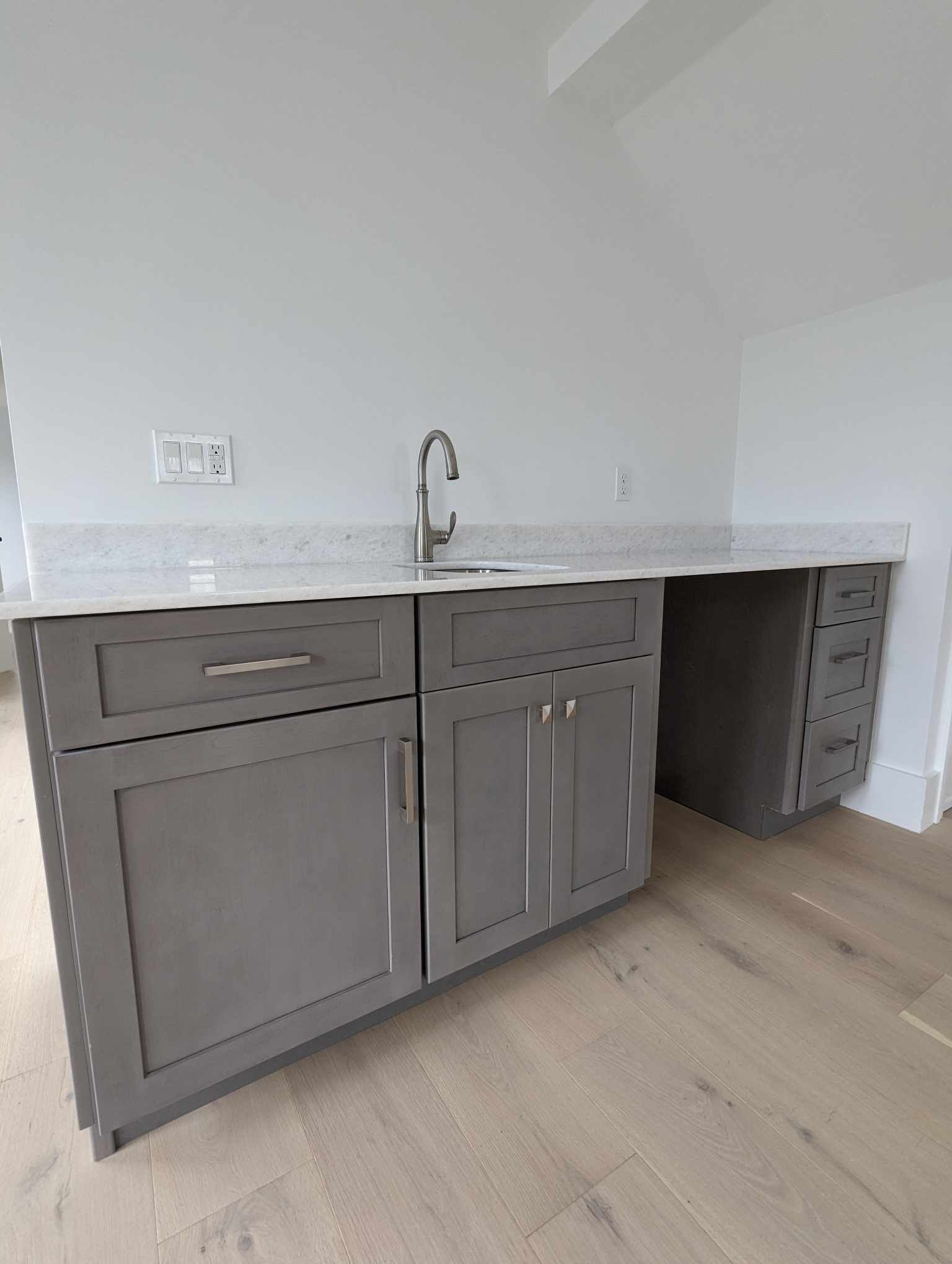 A kitchen with gray cabinets and a sink.