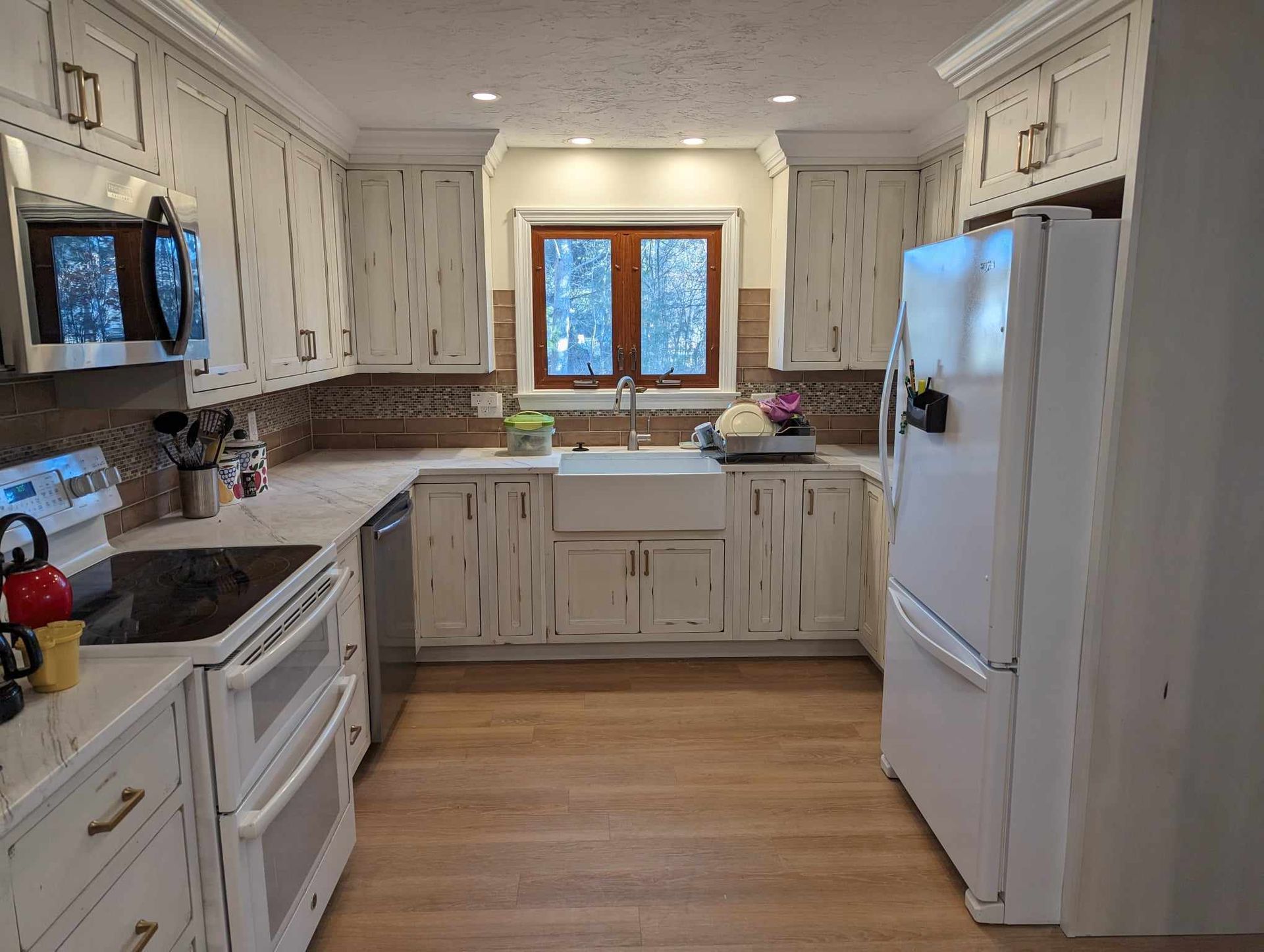 A kitchen with white cabinets , stainless steel appliances, a sink, and a refrigerator.