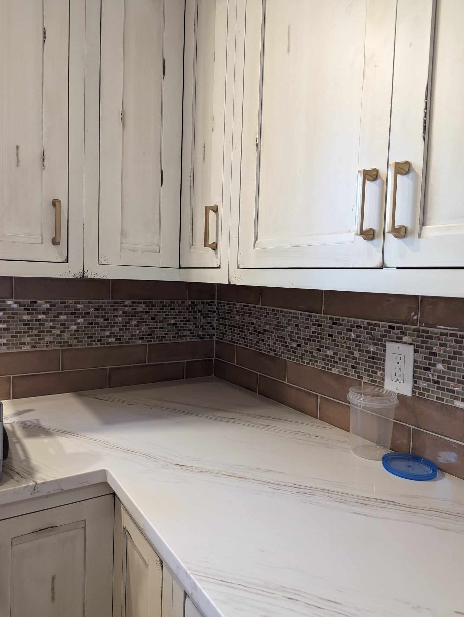 A kitchen with white cabinets and a white counter top.