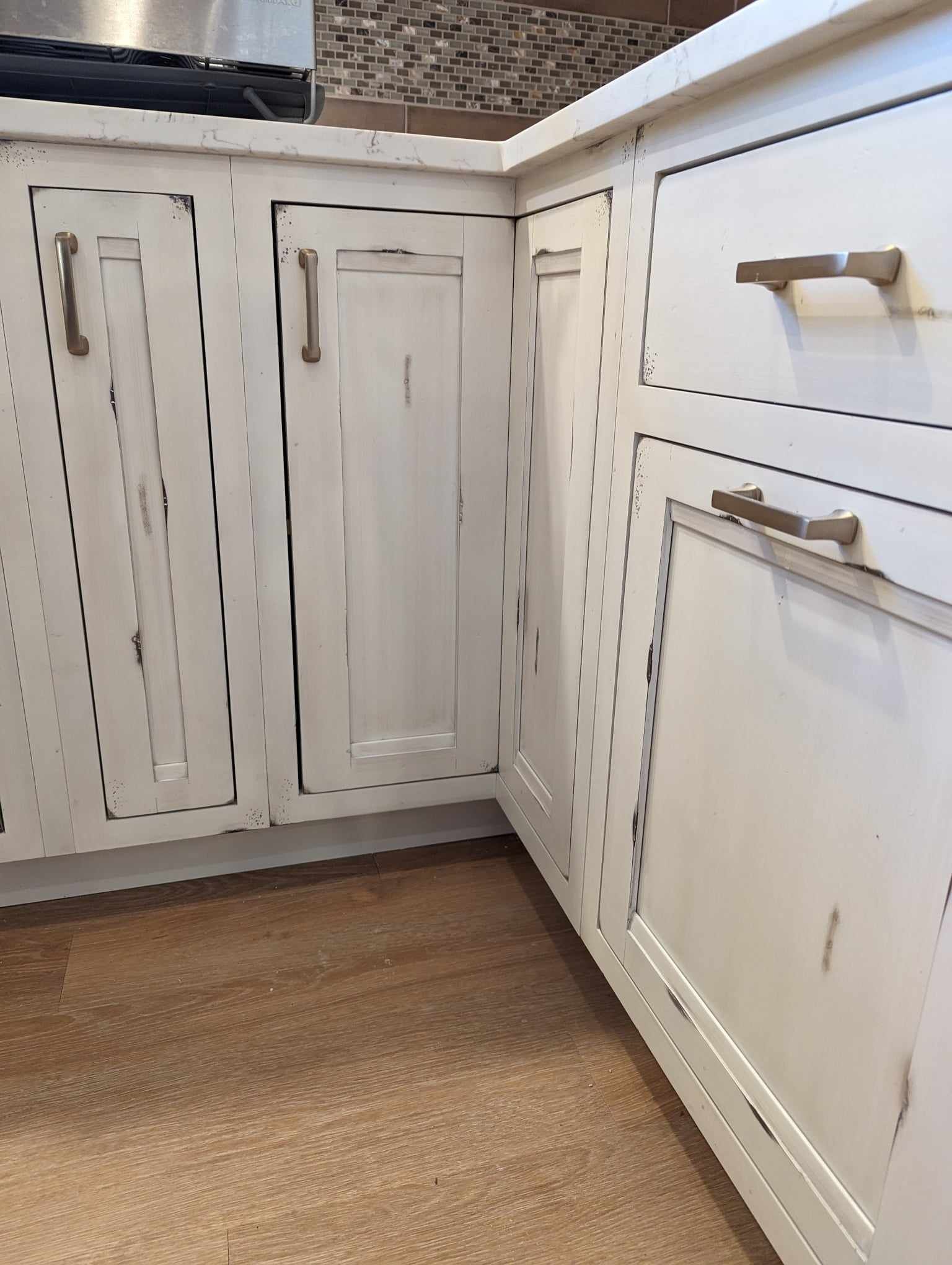A kitchen with white cabinets and drawers with brass handles