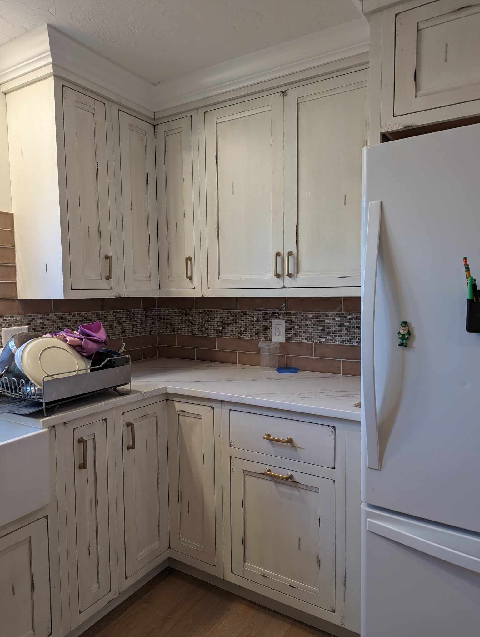 A kitchen with white cabinets and a white refrigerator.