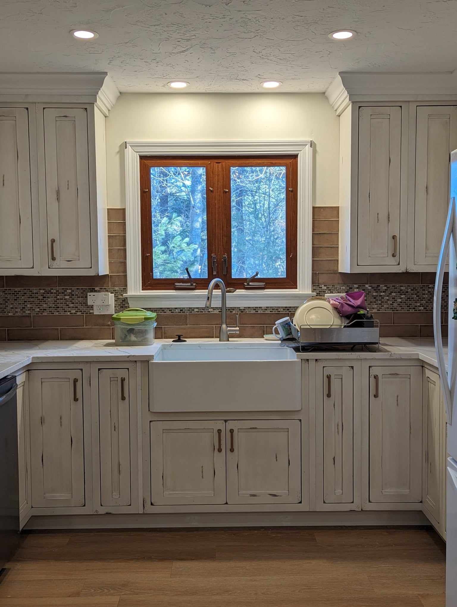 A kitchen with white cabinets, a sink, and a window.