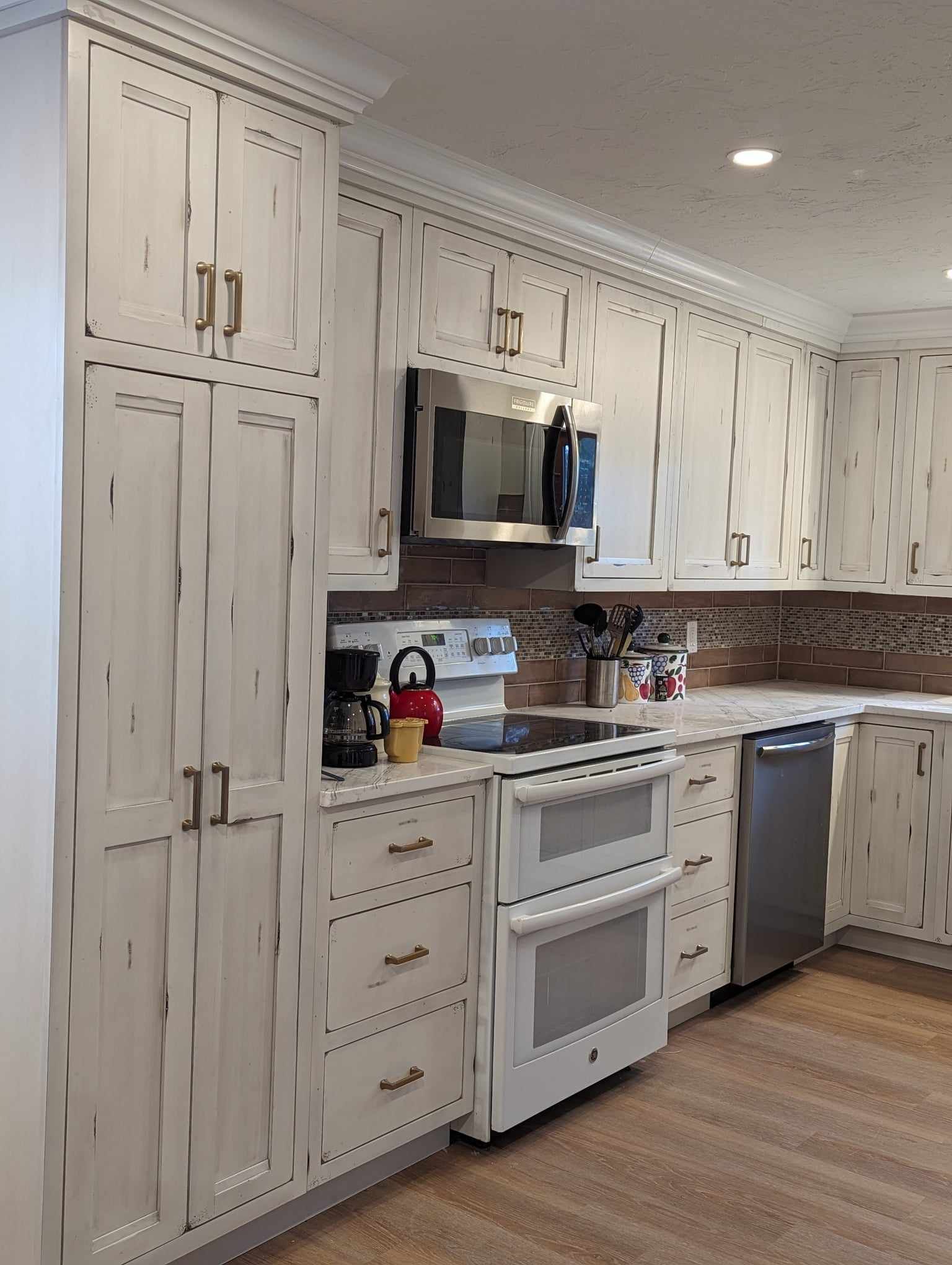 A kitchen with white cabinets, a stove, a microwave, and a dishwasher.