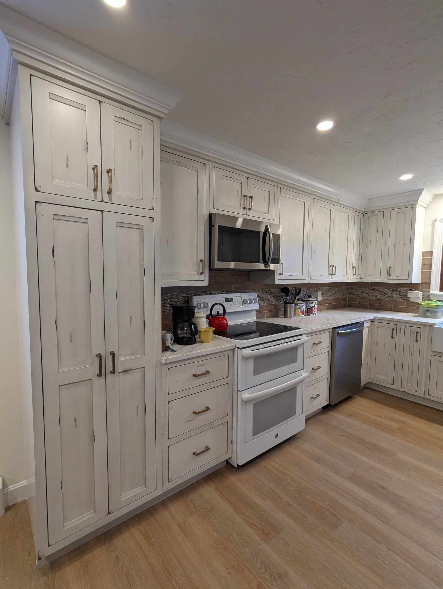 A kitchen with white cabinets, a stove, microwave, and dishwasher.