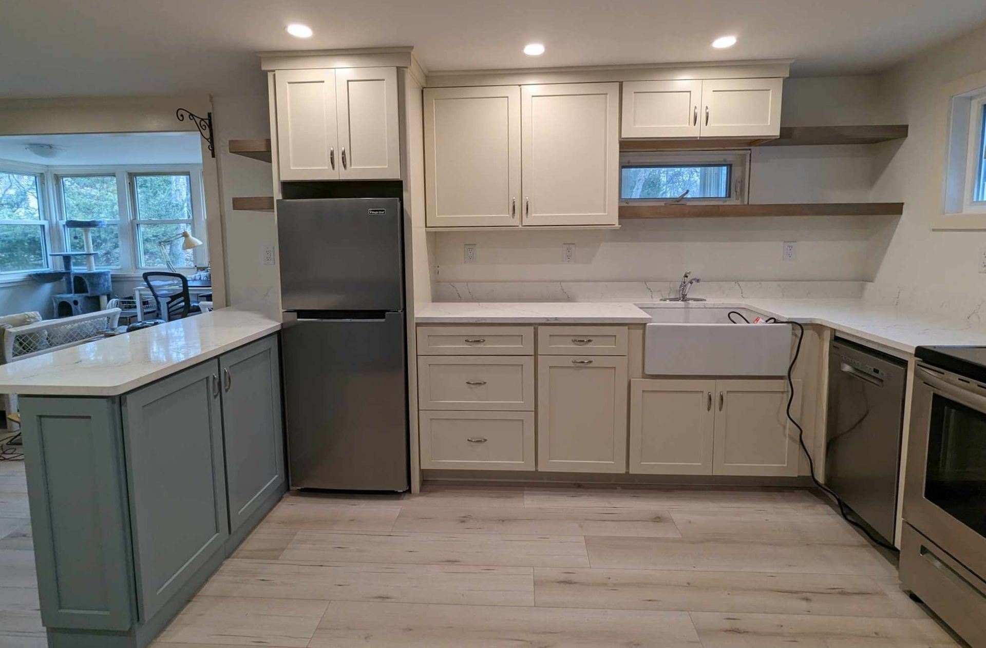 A kitchen with white cabinets, stainless steel appliances, a refrigerator and a sink.