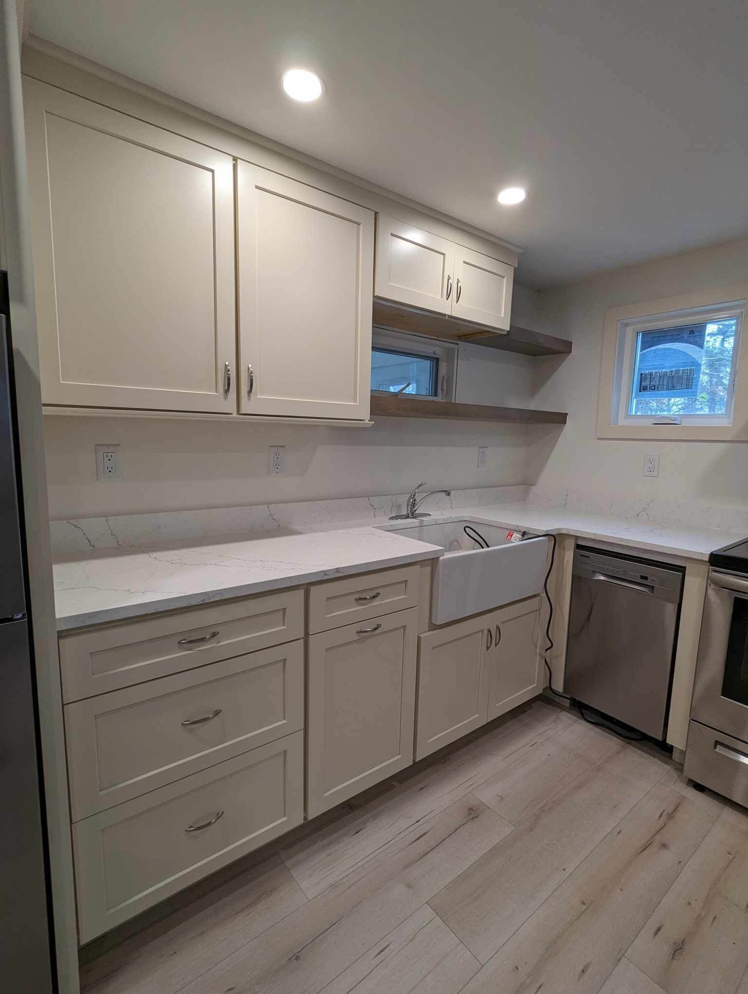 A kitchen with white cabinets, stainless steel appliances, a sink, and a window.
