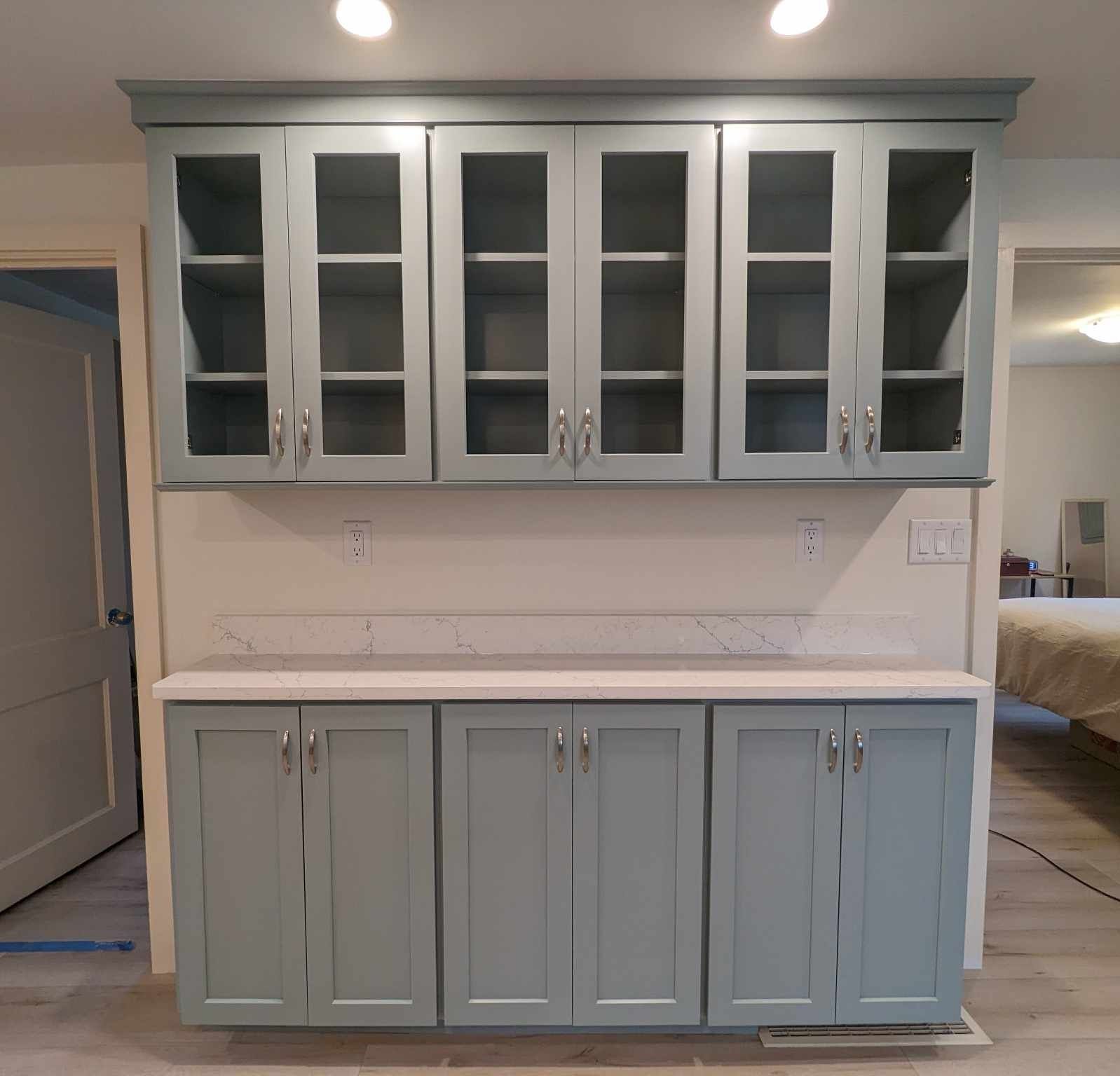 A kitchen with a lot of cabinets and glass doors.