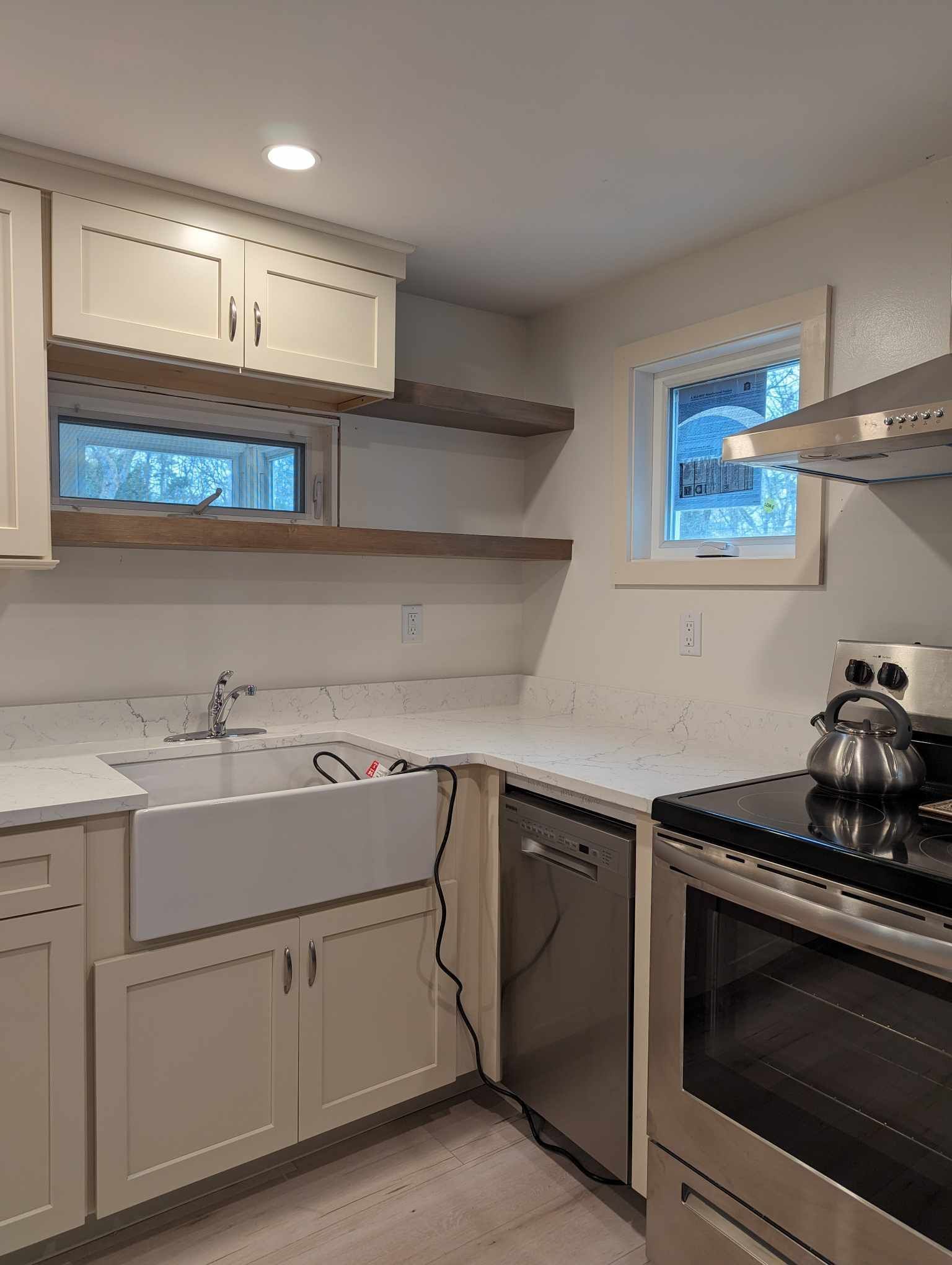 A kitchen with a sink, stove, dishwasher, and window.