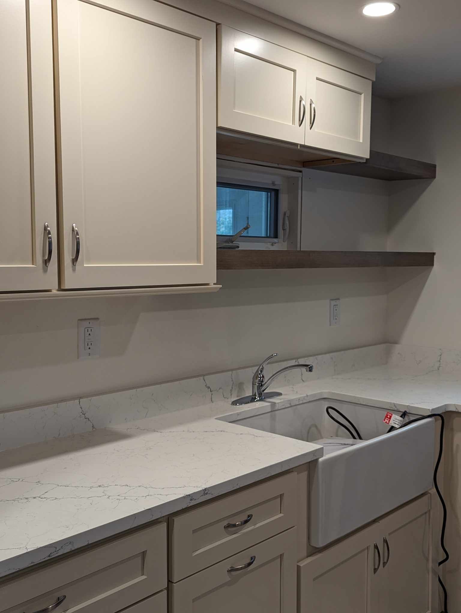 A kitchen with white cabinets, a sink, and a window.