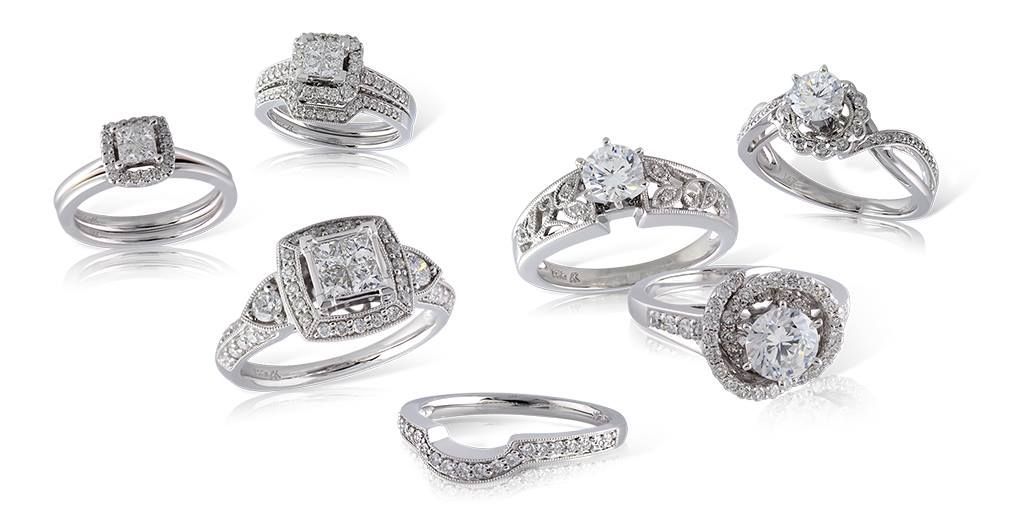 Seven diamond engagement rings on a white surface.