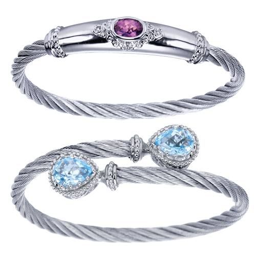 Two silver cable-style bracelets: one with a pink gemstone, the other with blue gemstones.