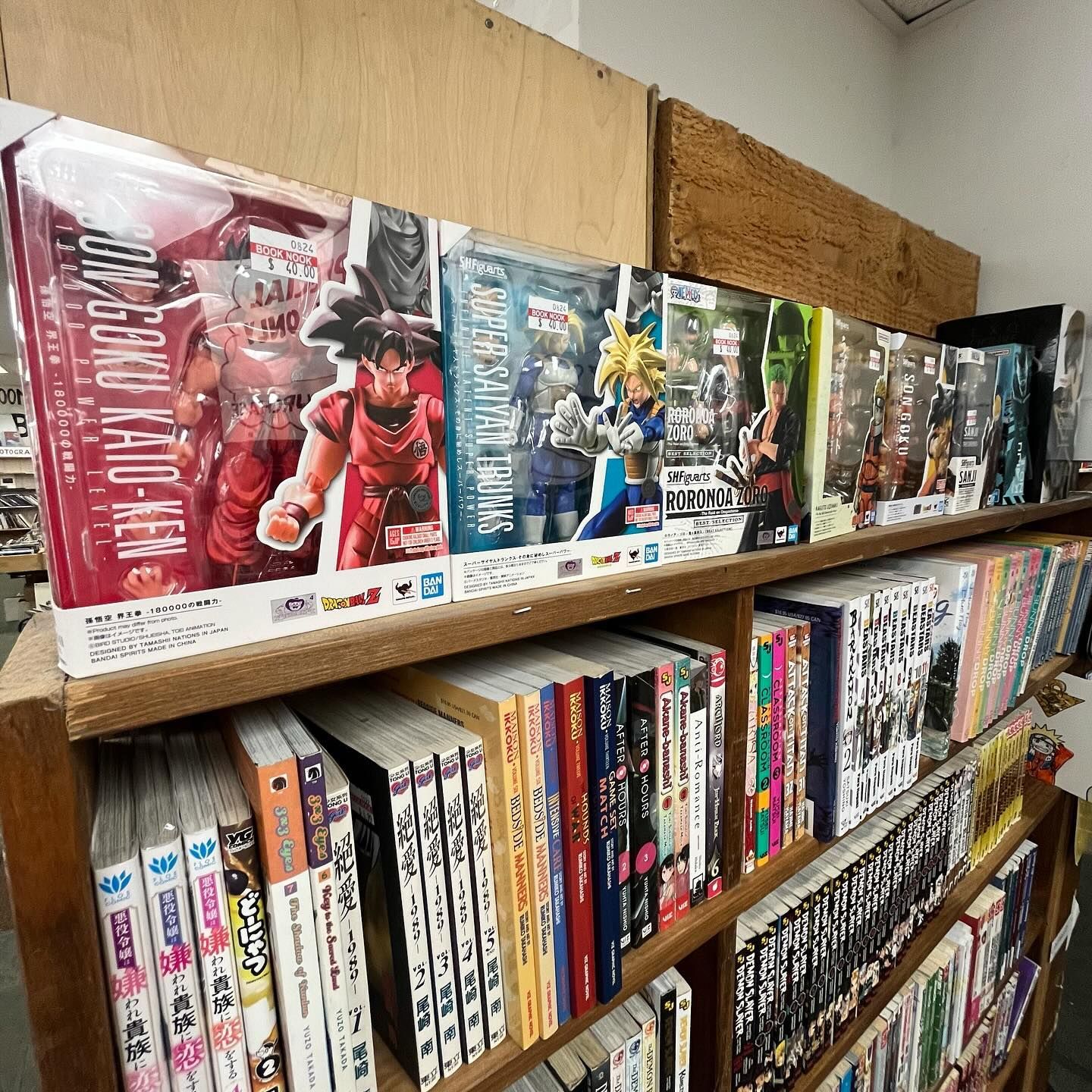 A shelf filled with books and figurines including one that says goku