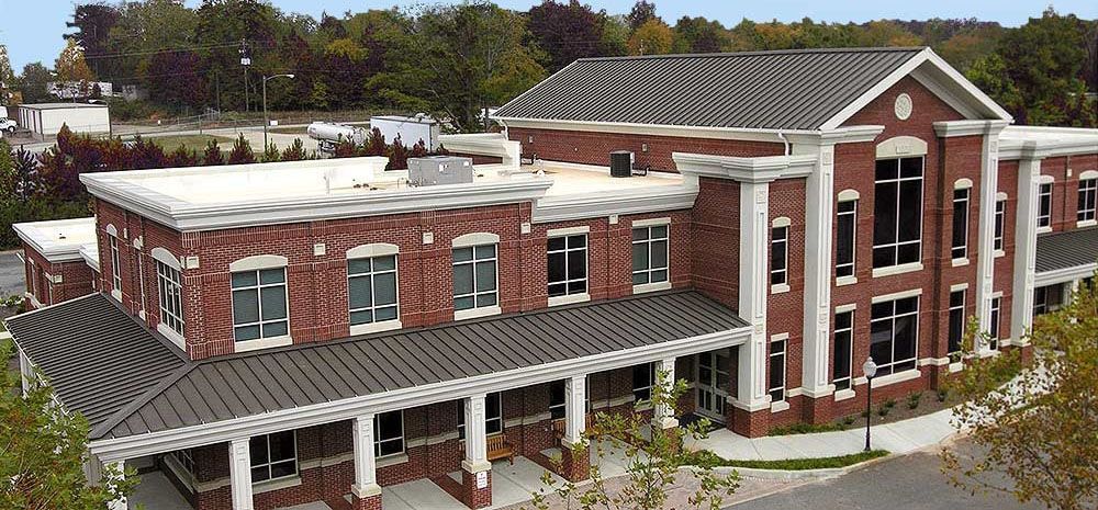 Aerial view of a red-brick academic building with a white-columned entrance and gray roof.