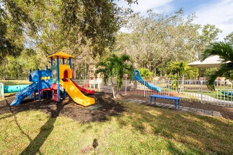 A colorful playground with a slide and a bench in a park.