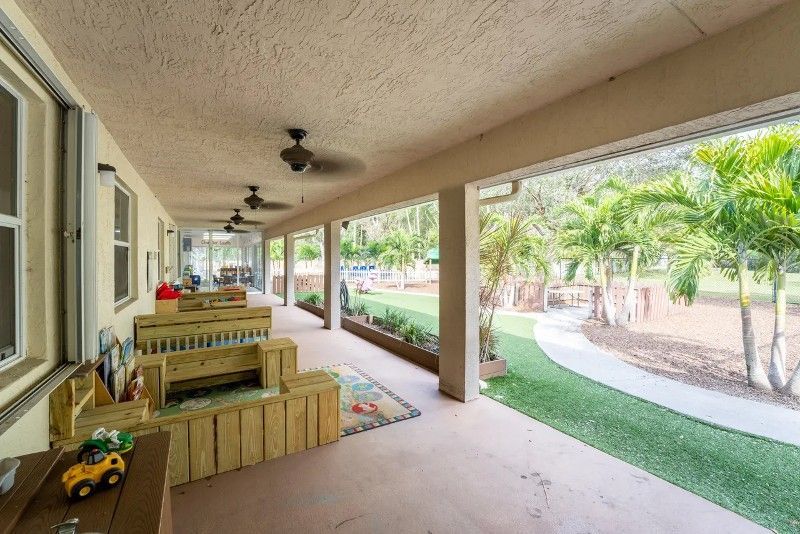 A large porch with a wooden bench and a toy truck on it.
