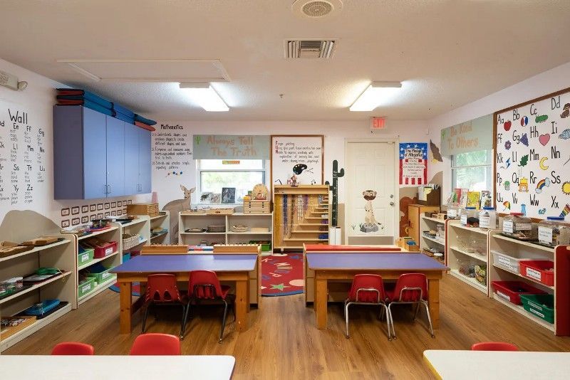 A classroom with tables and chairs and a bulletin board