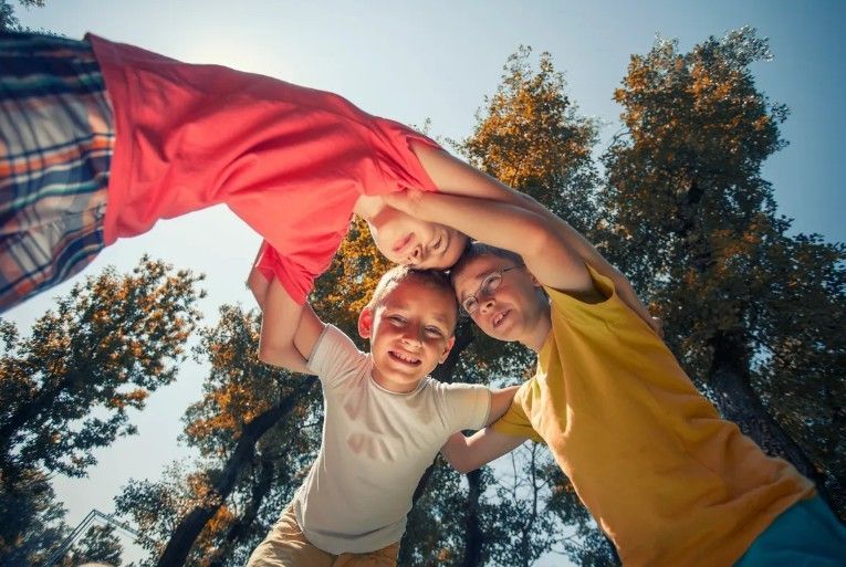 A group of children are standing in a circle with their arms around each other.